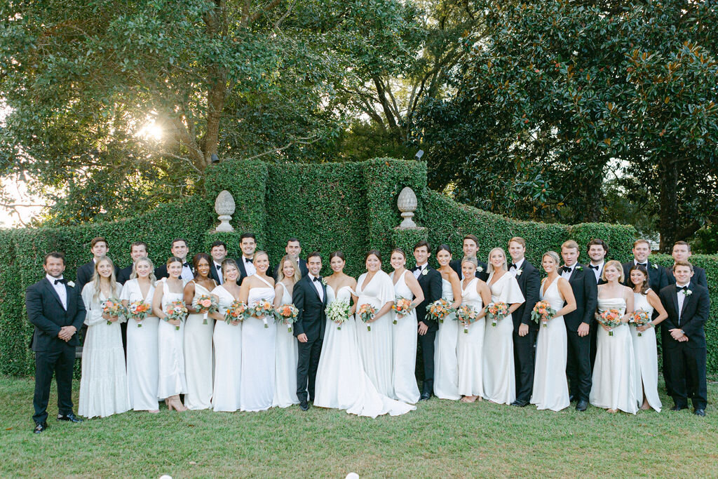 Bridesmaids in white dresses and groomsmen in black tuxedos