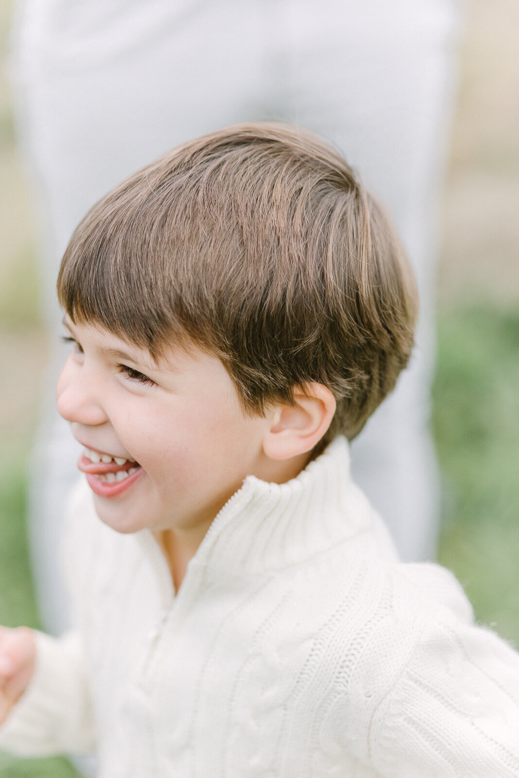 A young boy smiling and laughing with his tongue slightly sticking out