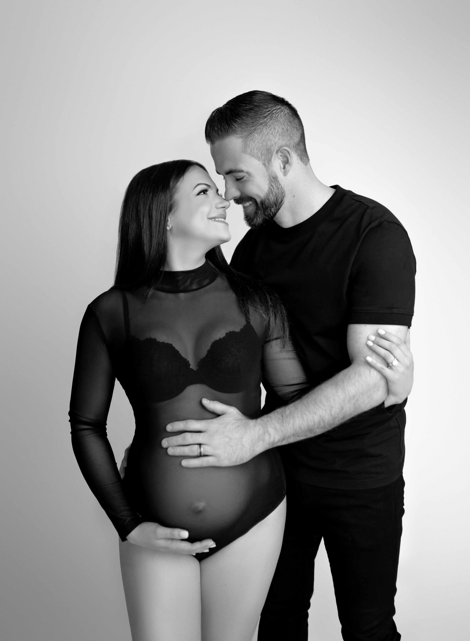 Mom in black body suit and Dad in black shirt, hugging and smiling. Photo taken by Atlanta Maternity Photographer- Jenni Nikki in Woodstock, GA.