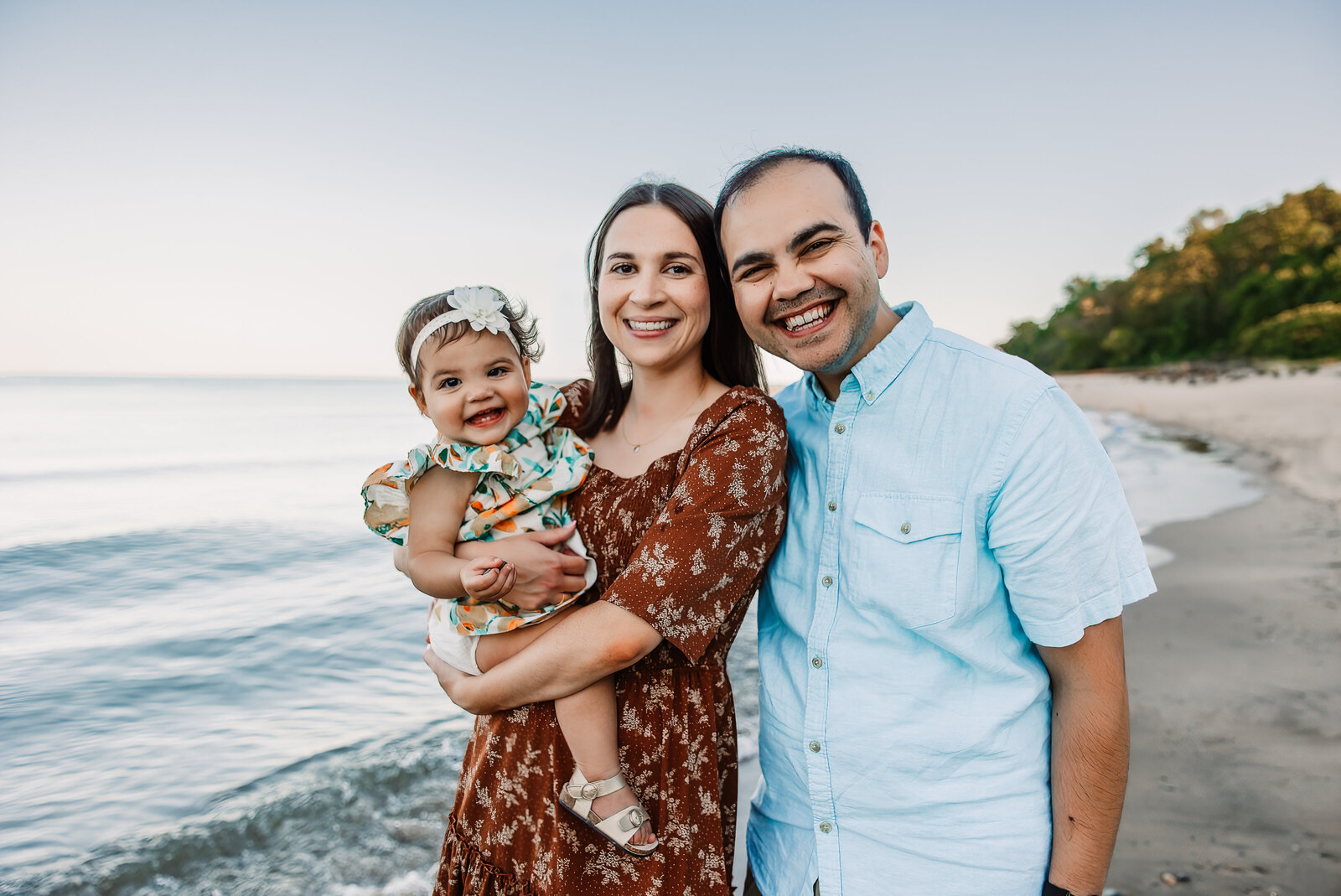 A happy family smiles while walking on a beach at sunset