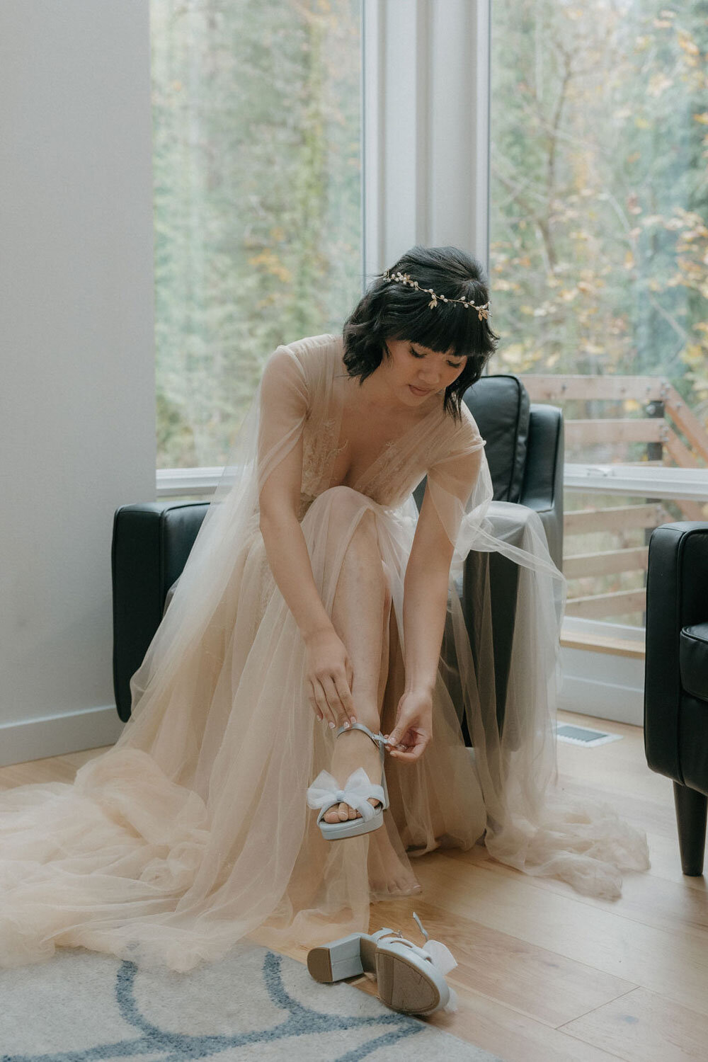 Bride in gown sitting and fastening her shoes