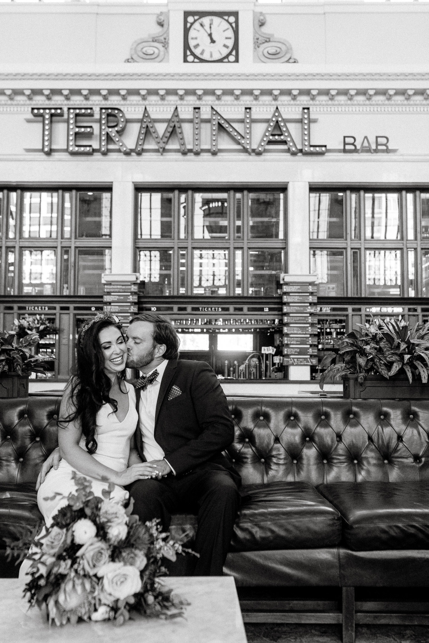 Union station small wedding groom kisses bride on the cheek in stunning urban black and white photo.