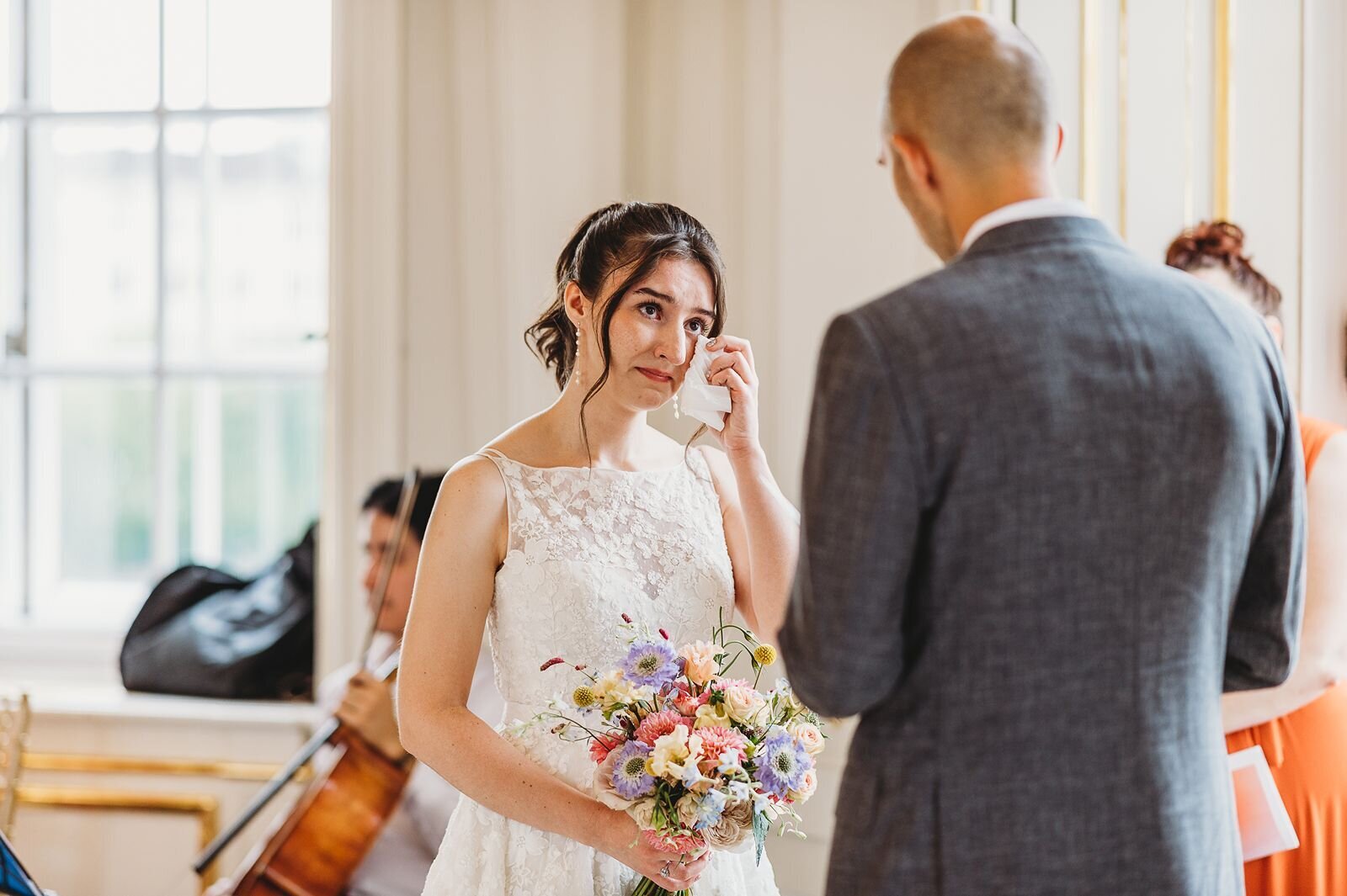 bride wipes away tears during wedding ceremony