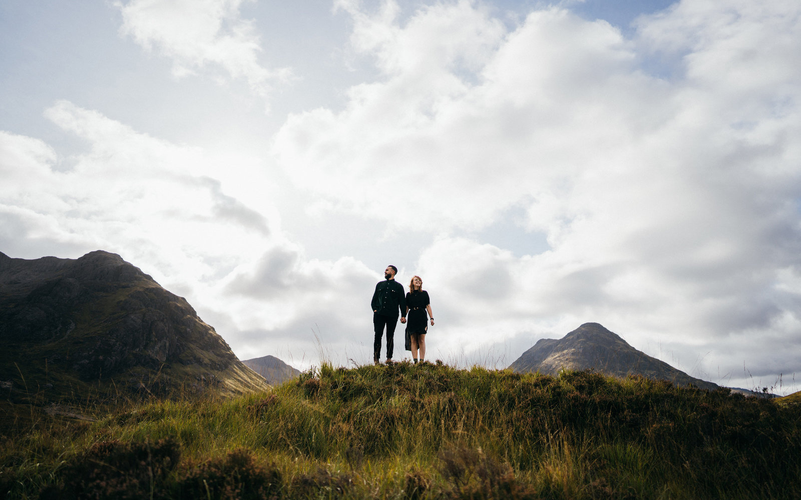 Loving engaged couple standing on a hill in Glencoe, Scotland