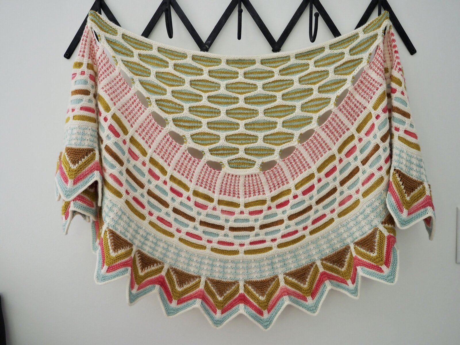 Hand knit shawl hanging on hooks