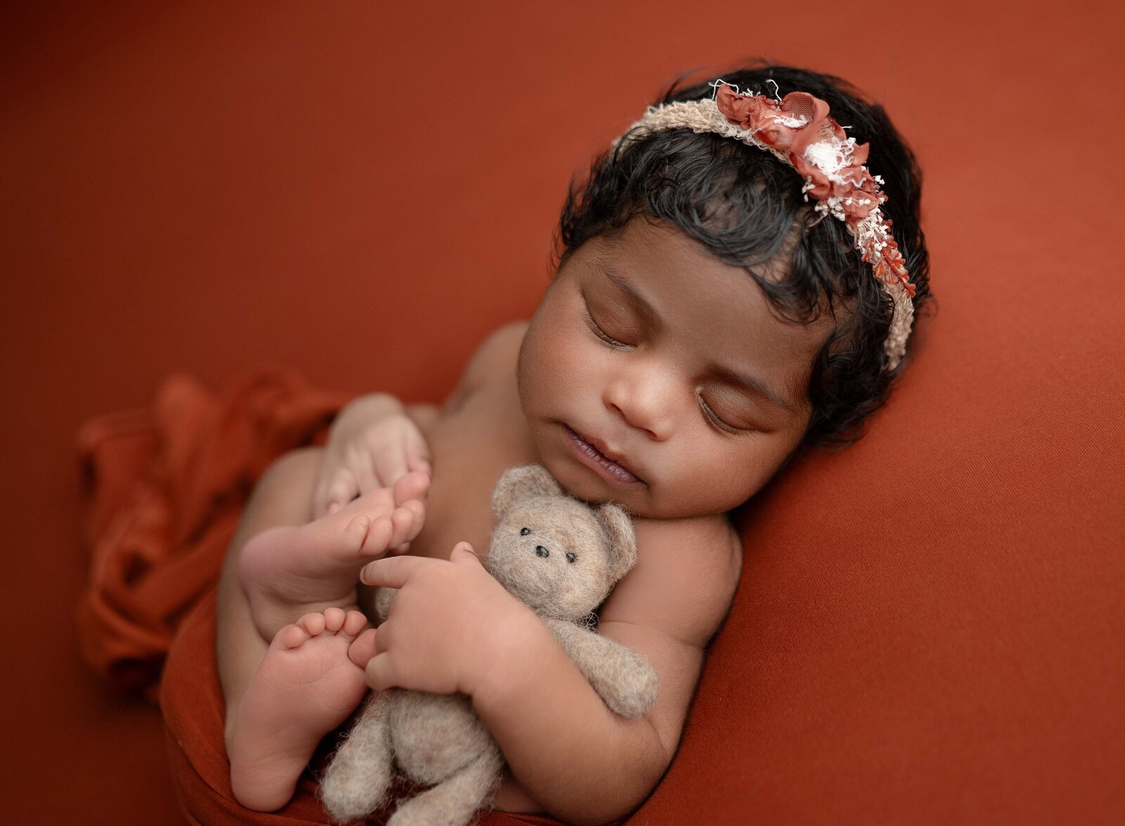 Newborn baby girl with dark hair, sleeping and holding brown teddy bear. Newborn Photography in Marietta GA by Jenni Nikki Photography.