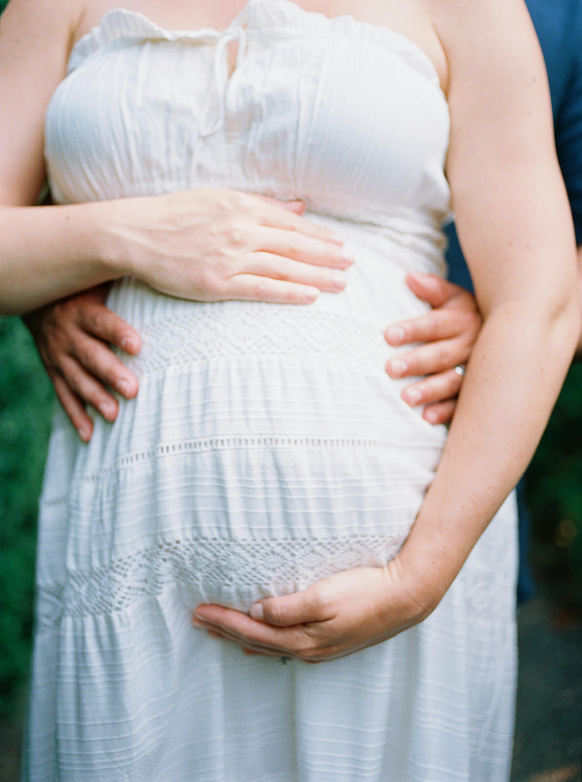 Close-up of parents’ hands gently cradling a baby bump, celebrating new life.