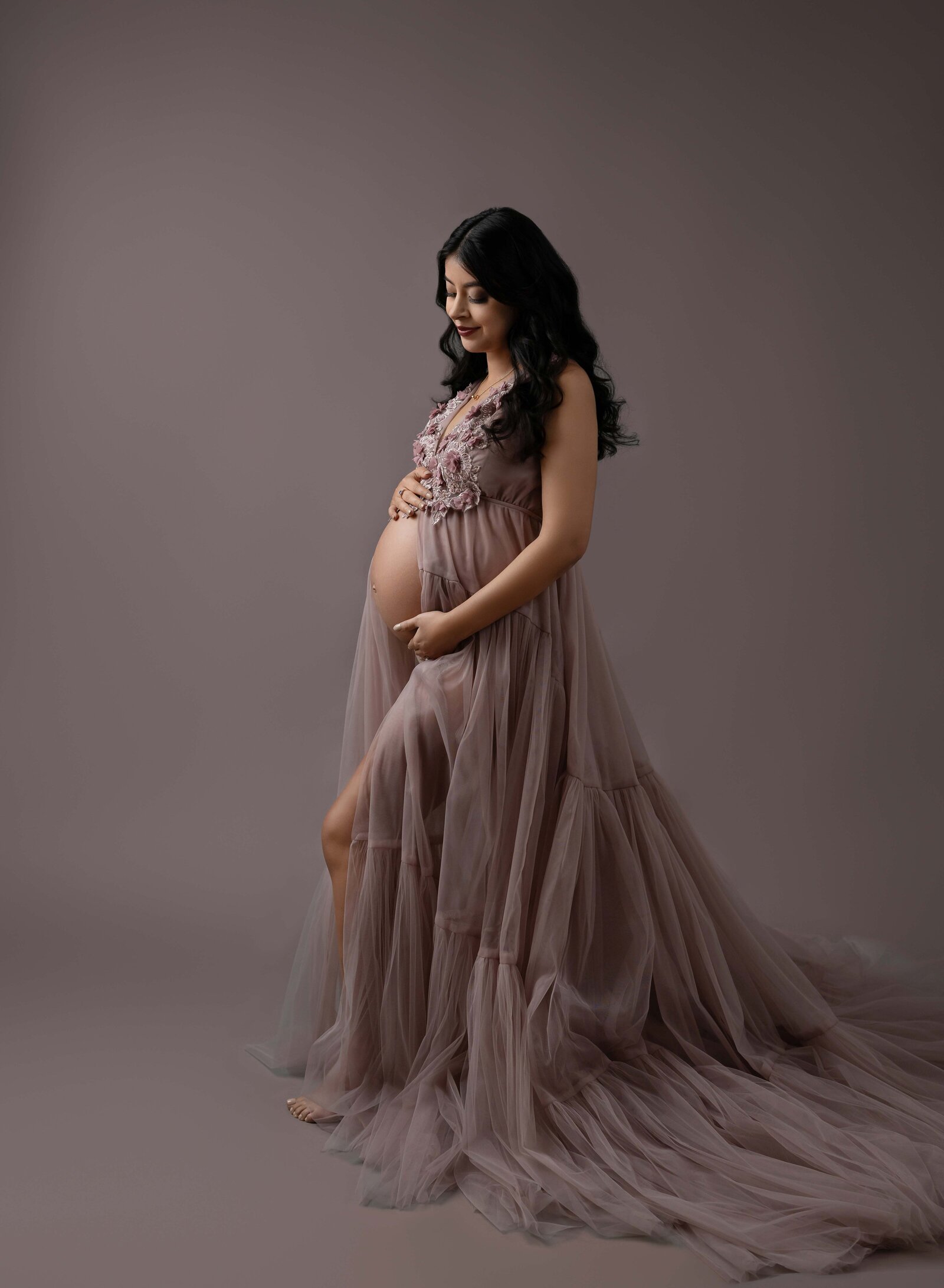 Mom wearing mauve tulle dress and looking down at baby bump. Pregnancy photo taken by Jenni. Nikki Photography at Atlanta Photo Studio. 