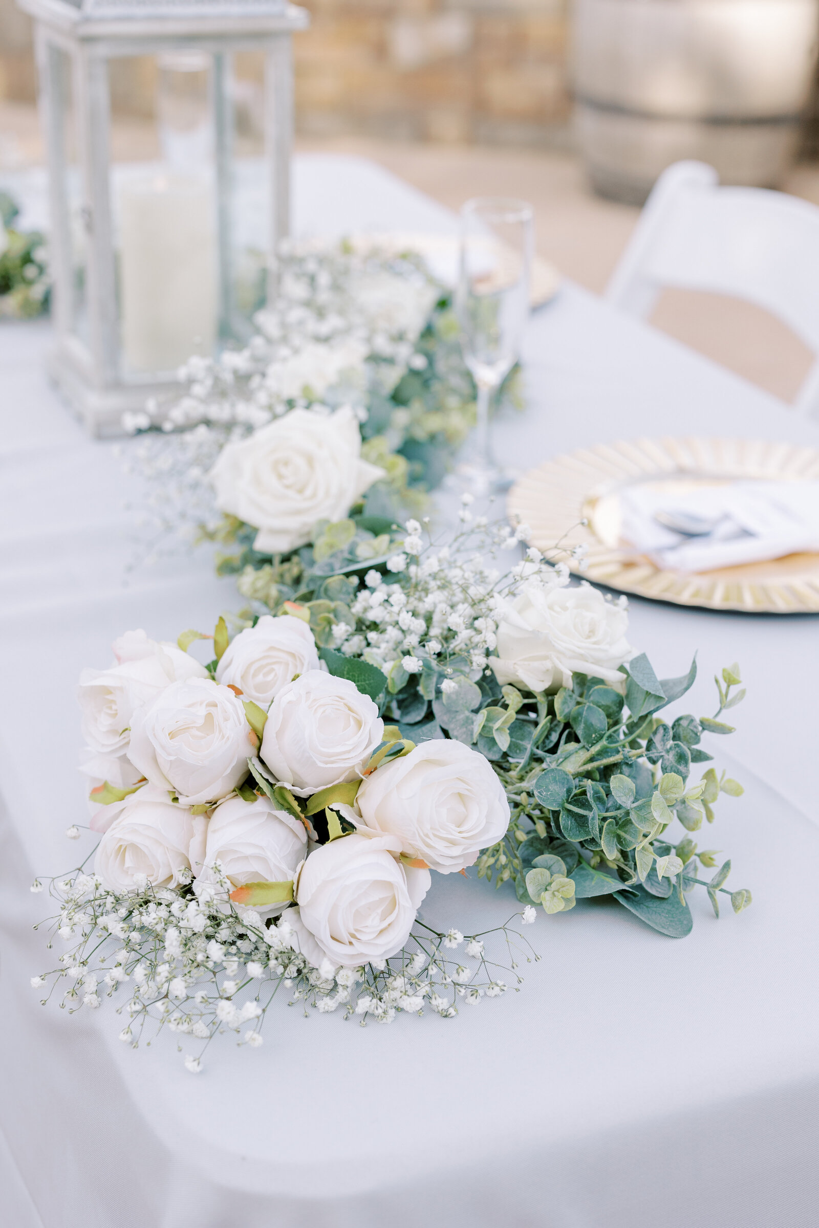 detail shot of white roses, eucalyptus and babies breathe as a centerpice for wedding decor at a reception captured by sacramento wedding photographer