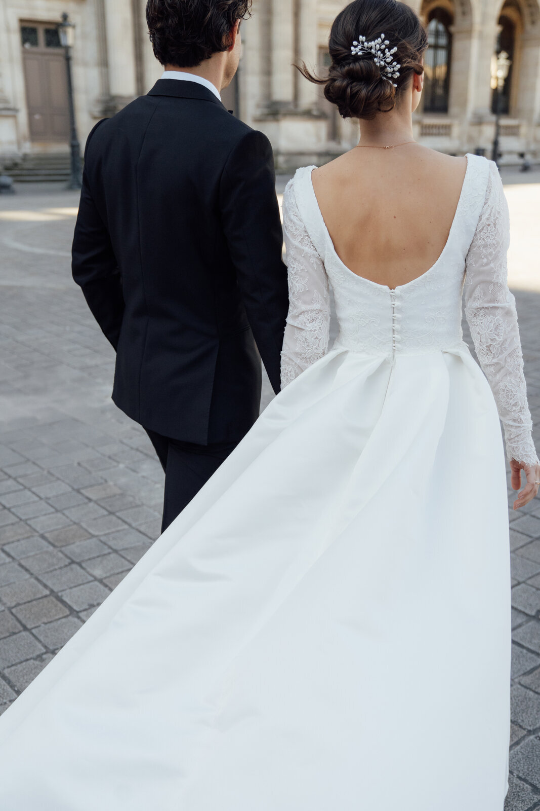 Trouwjurk met diepe ruglijn en knoopjes satijnen rok met plooi en een elegante super lange sleep een klassieke en tijdloze bruidslook voor een stijlvolle bruiloft