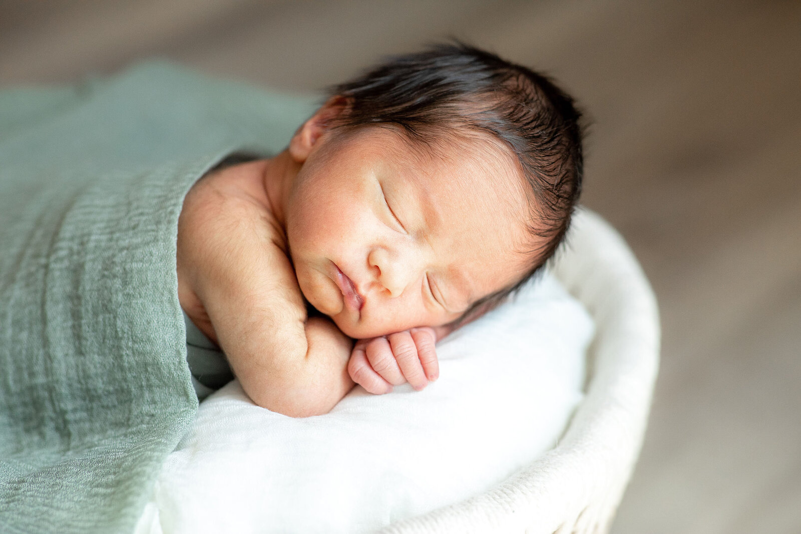 sleeping baby in a basket with a green blanket