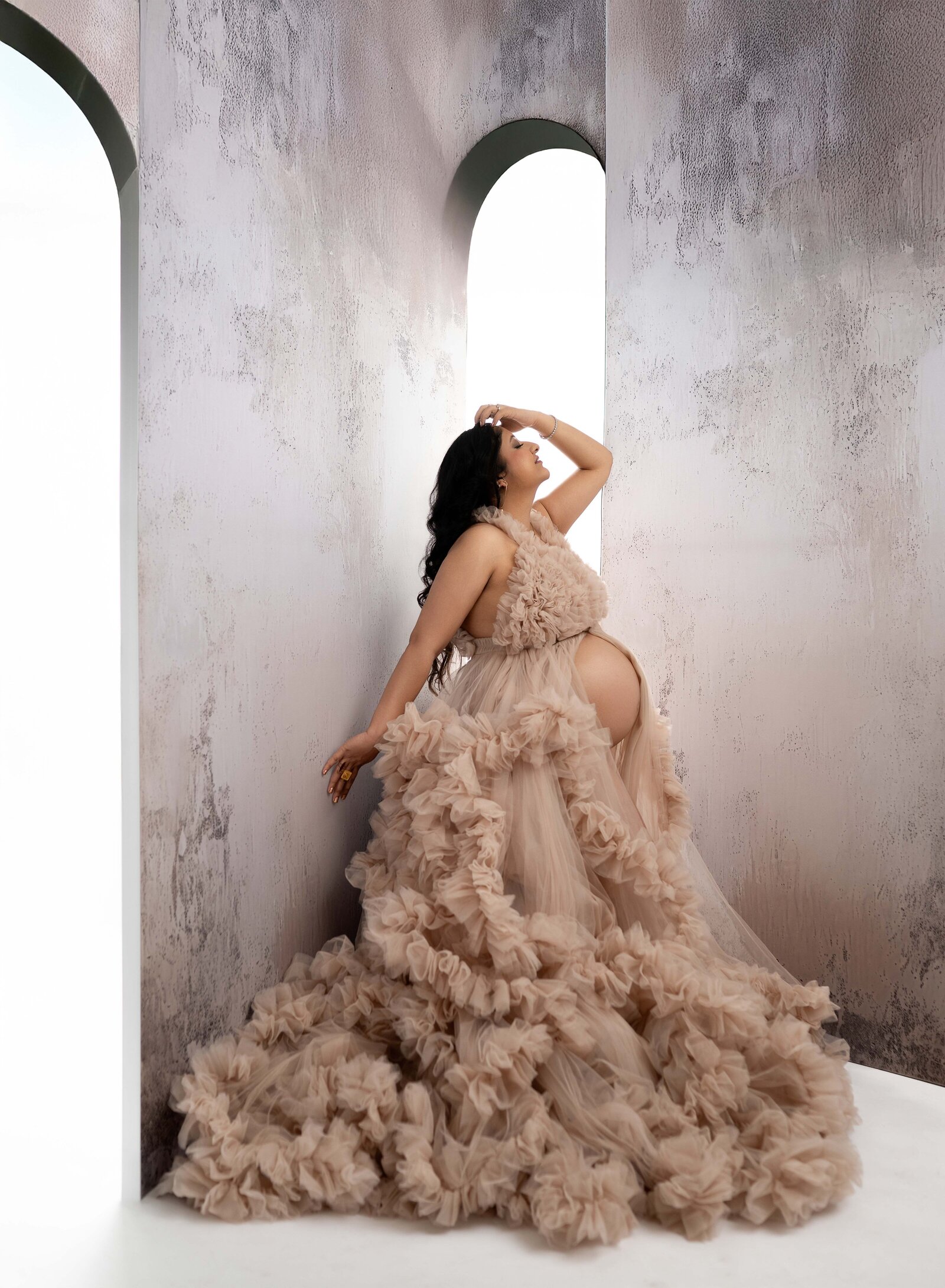 Arch wall panels with pregnant Mom in ruffled cream dress looking up and posing. Photo taken at Atlanta Maternity photo studio in Woodstock, GA.