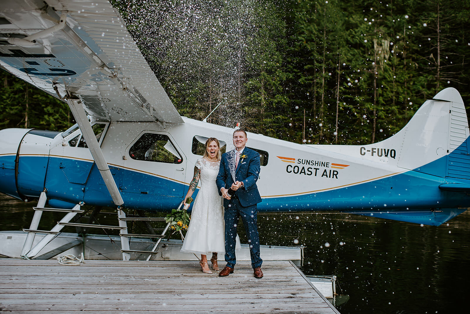 Couple spraying champagne infront of their float plane transportation during their adventure elopement