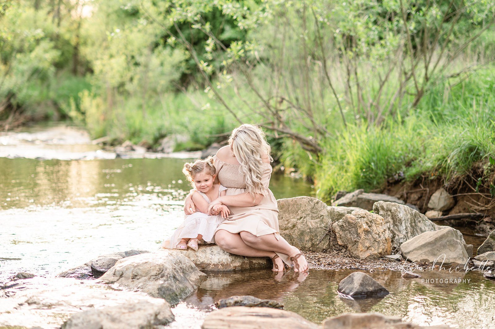 pregnant mother and daughter sitting on rocks in a small creek by york pa photographer