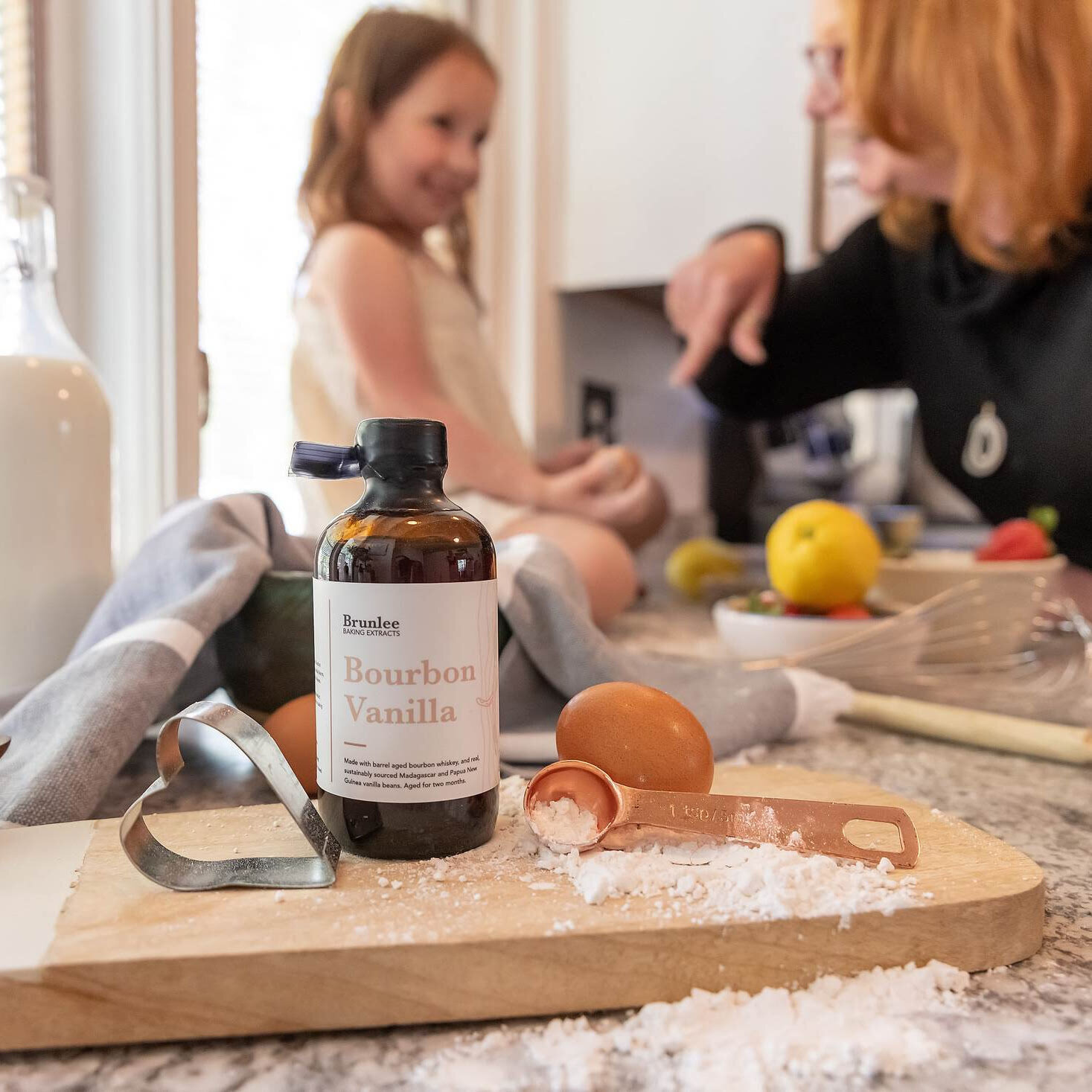 girl baking with mom and using vanilla extract