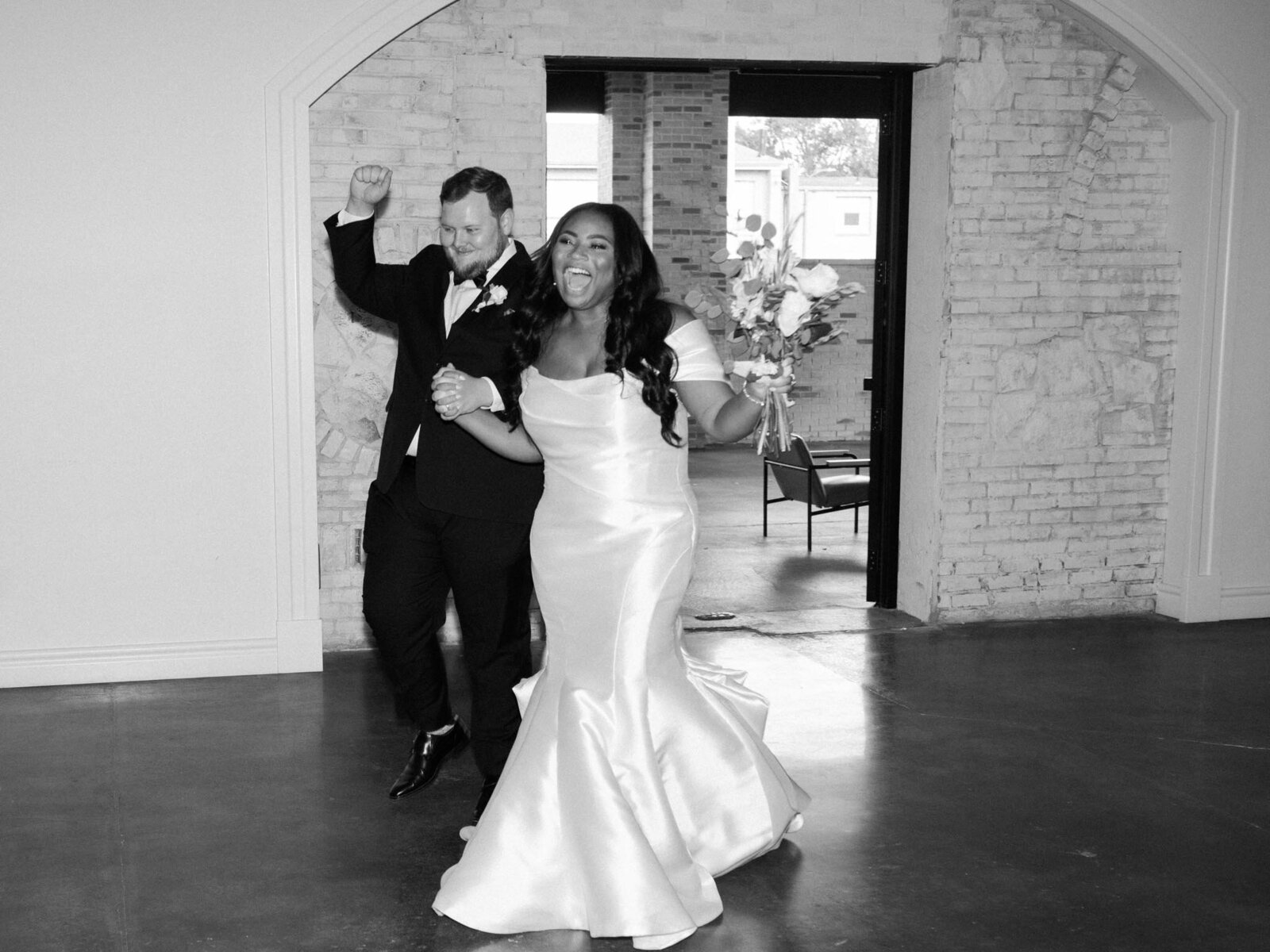 bride and groom joyfully enter their wedding reception, smiling and celebrating at grbic events, a wedding venue in st. louis