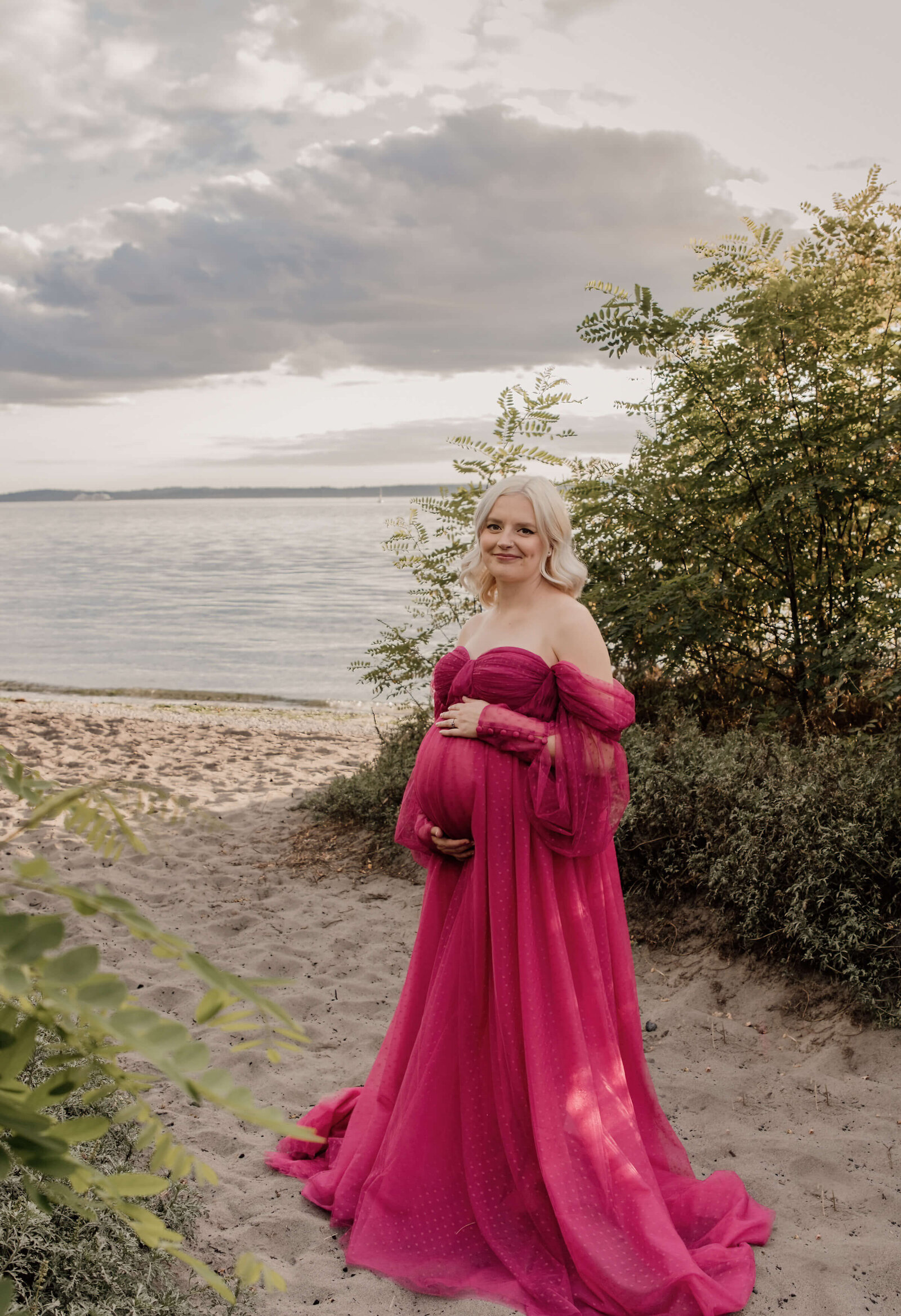 Pregnant woman standing on the sandy beach.