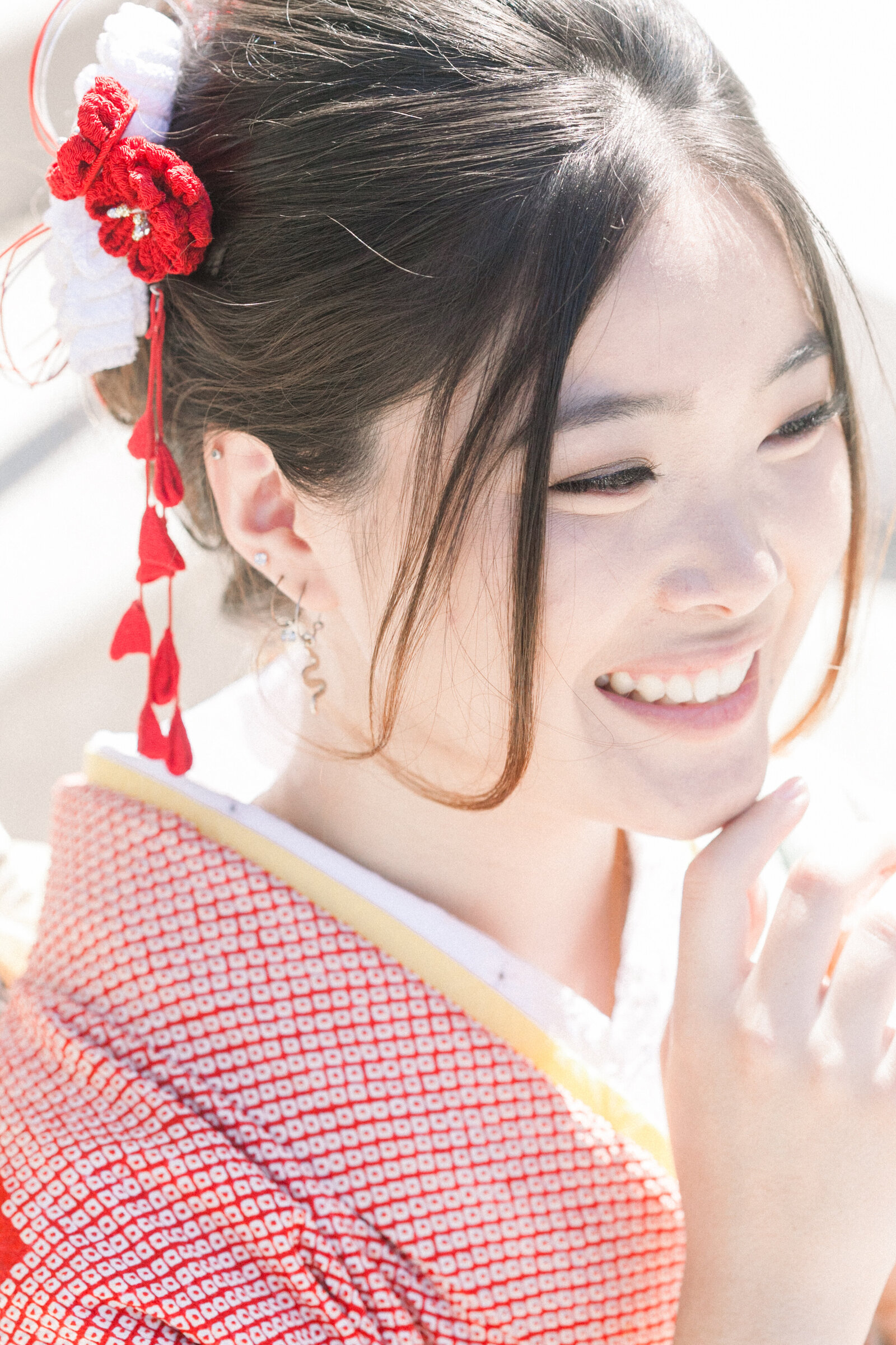 Smiling close-up portrait of a young woman in a red furisode kimono with floral hair ornament at Brand Park Glendale during her Seijinshiki (coming-of-age) celebration, kimono rental in Los Angeles | ロサンゼルス・ブランドパークでの成人式。赤い振袖と髪飾りの女性が笑顔を見せるクローズアップポートレート、着物レンタル