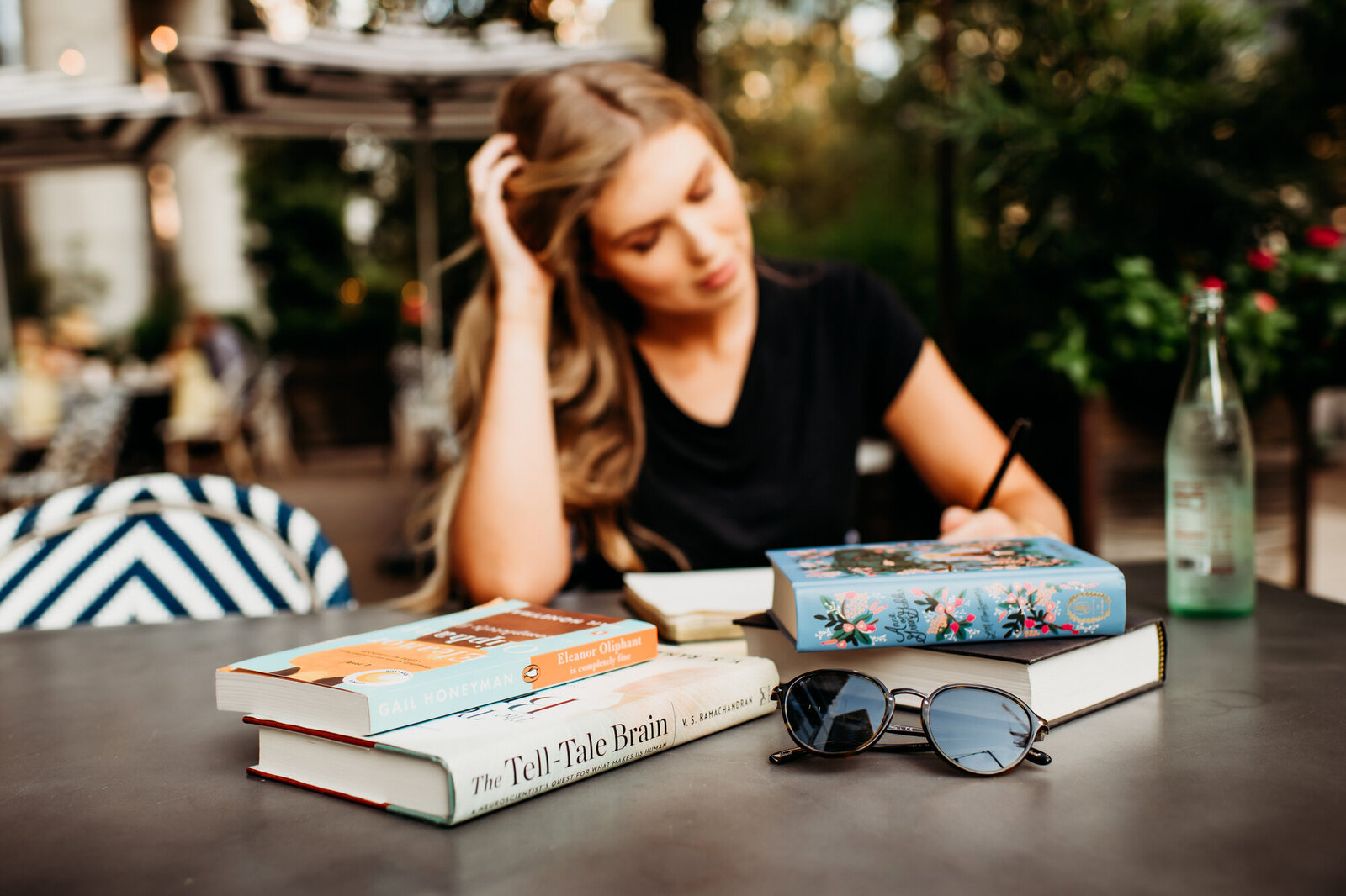 Branding Photographer, a woman sits at a table outside with books on the table before her