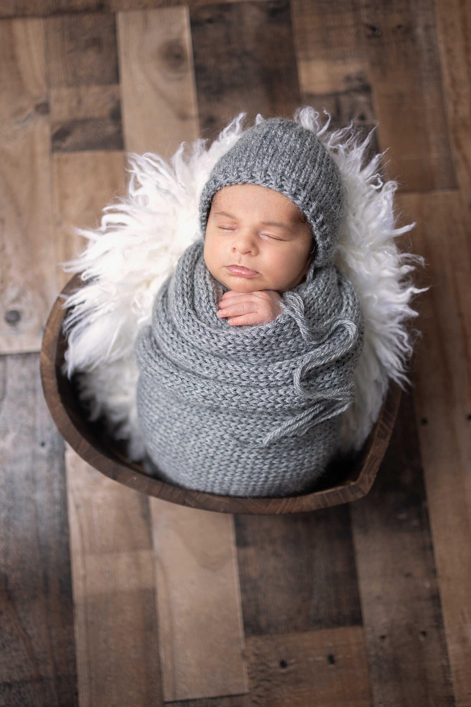 Sleeping newborn swaddled in a wrap laying in a heart bowl during and in studio session in Waldwick, NJ