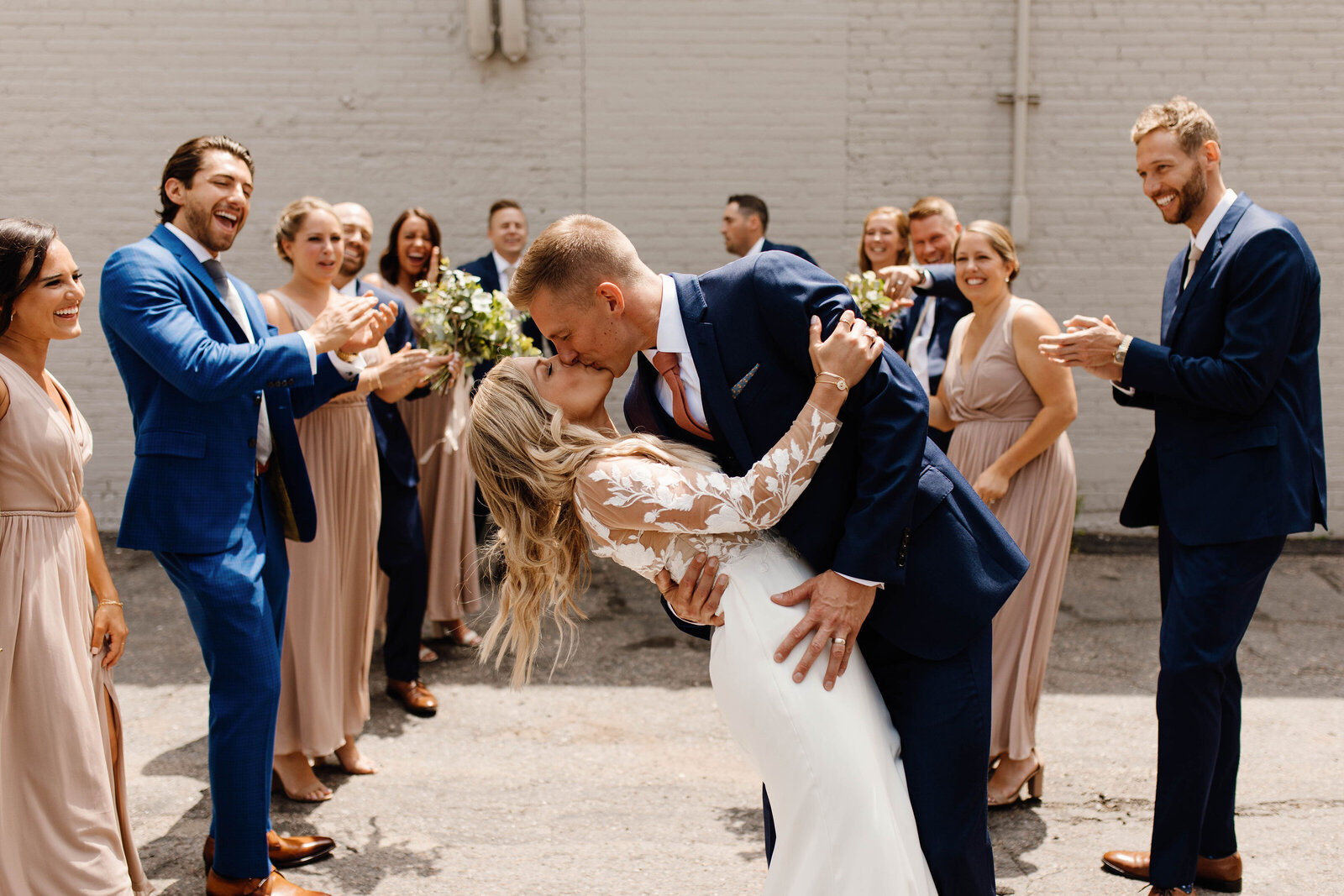 Bride and groom kissing while their bridal party is cheering them on