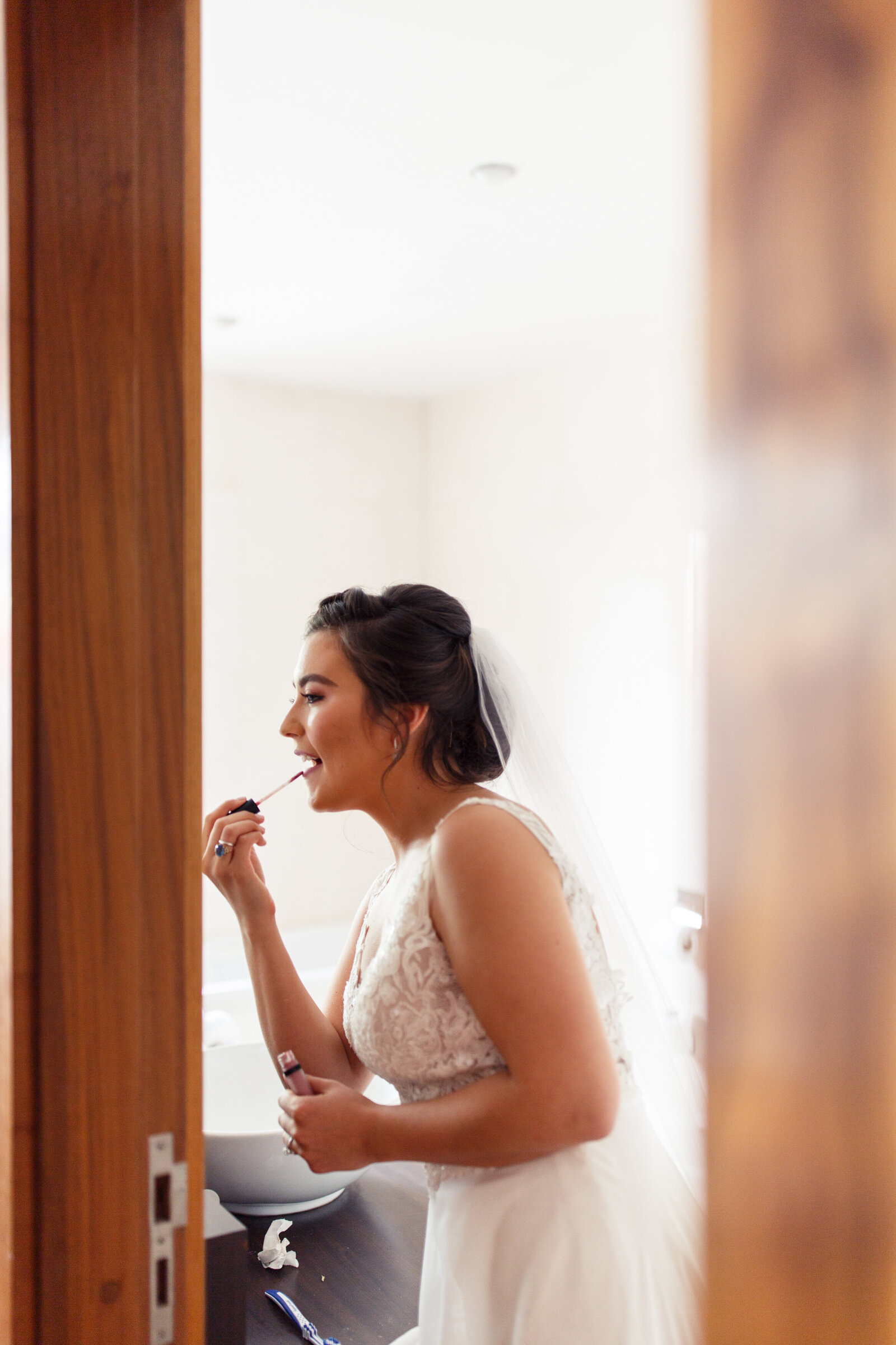 bride putting on lip gloss before leaving for her elopement