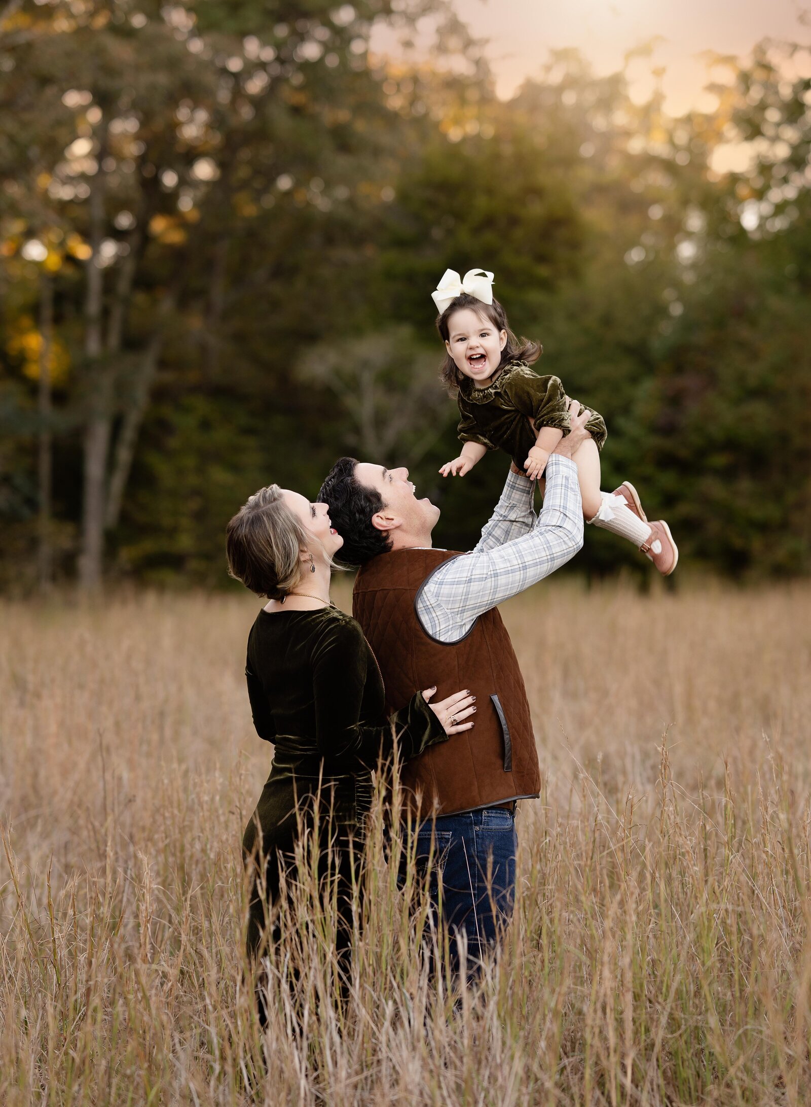 Dad tossing baby in air and she is laughing big. Fall photos taken by Atlanta family photographer.