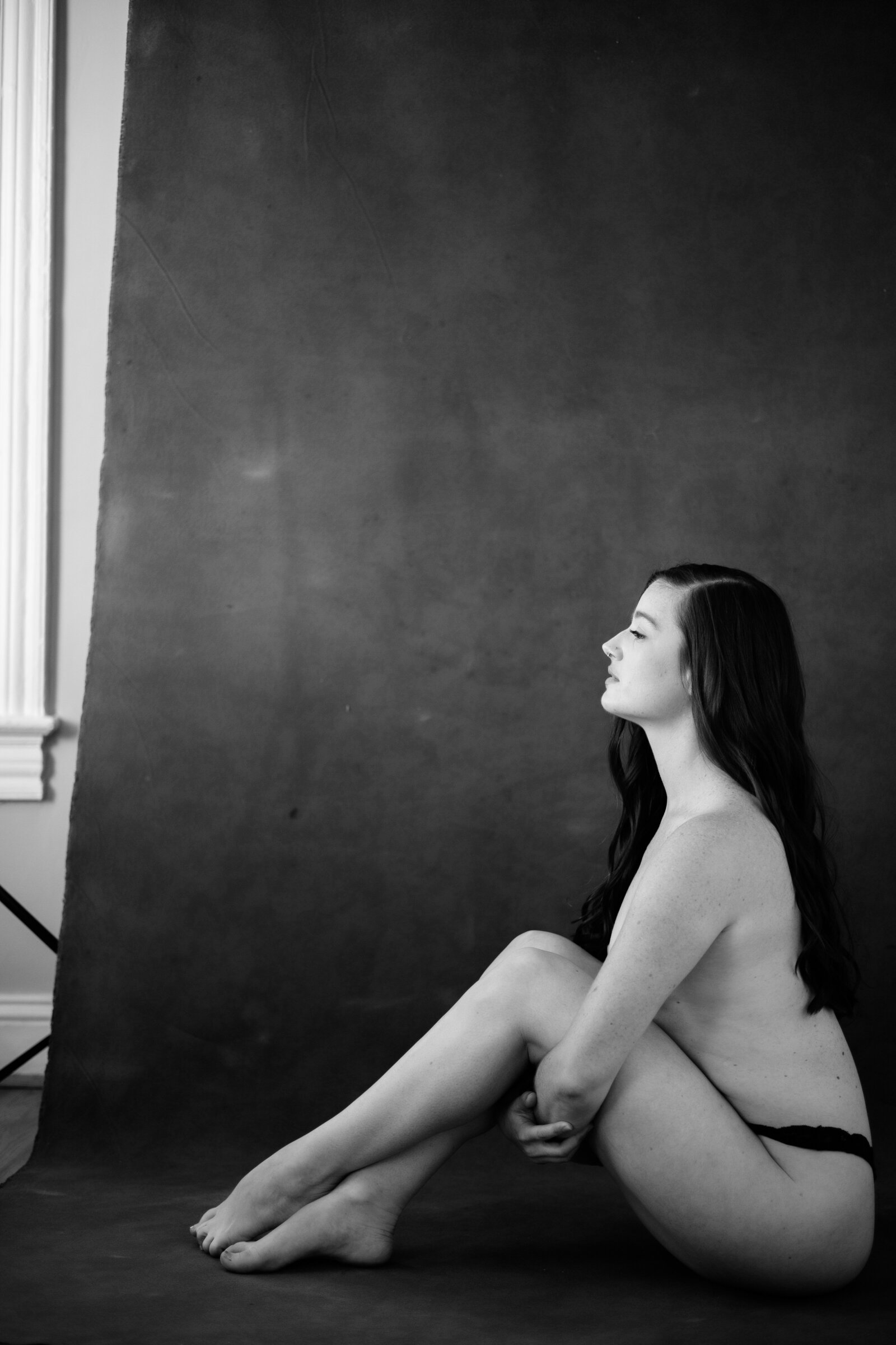 Black and white boudoir photo of woman wearing black thong