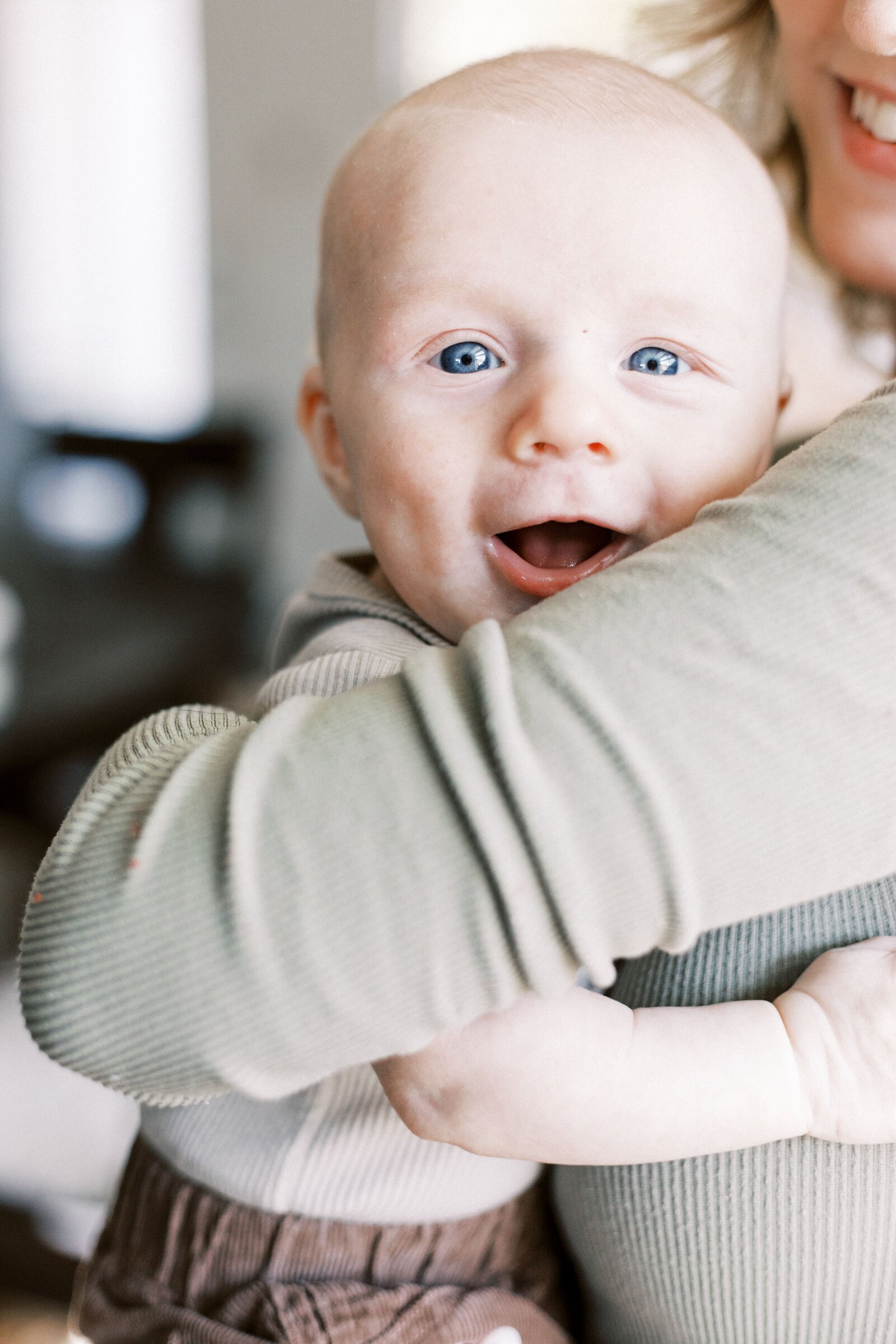 baby smiling over mom's arms during lifestyle family photos in peoria illinois 