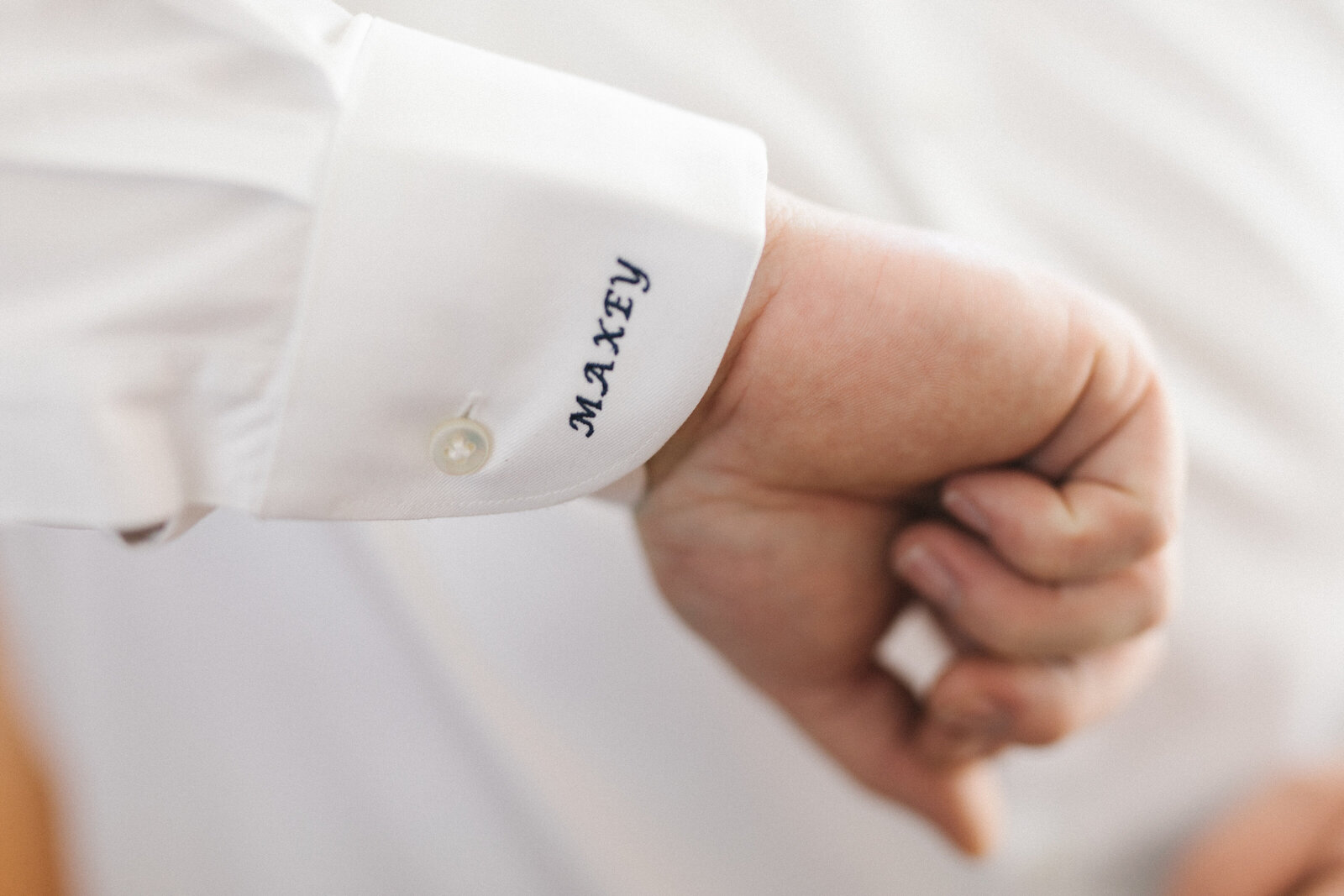 Groom wearing custom white shirt with embroidered cuff details
