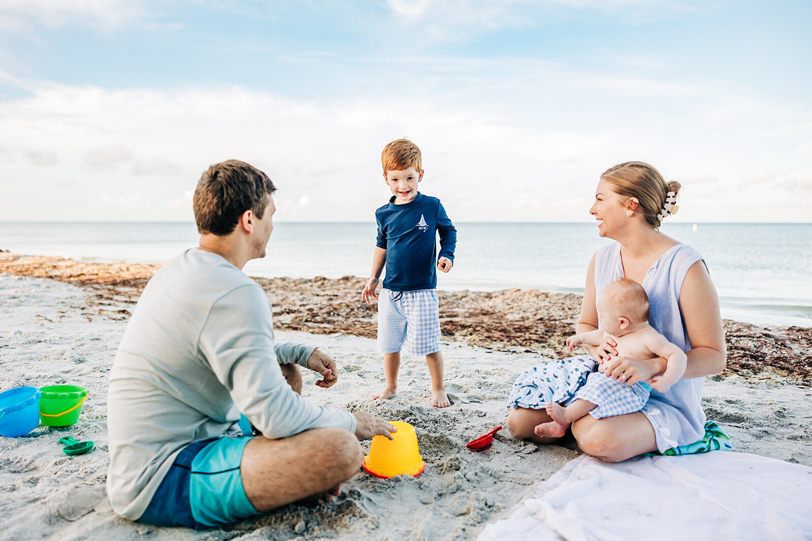 a candid photo of a relaxed family with two young boys building sand castles on the beach near st. pete