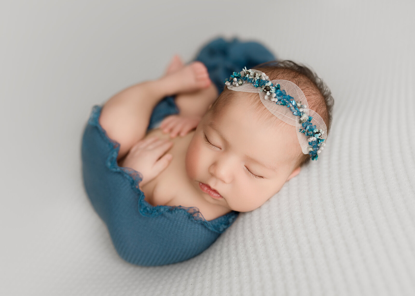 baby in blue located in oswego ny studio on white backdrop in studio newborn photo shoot