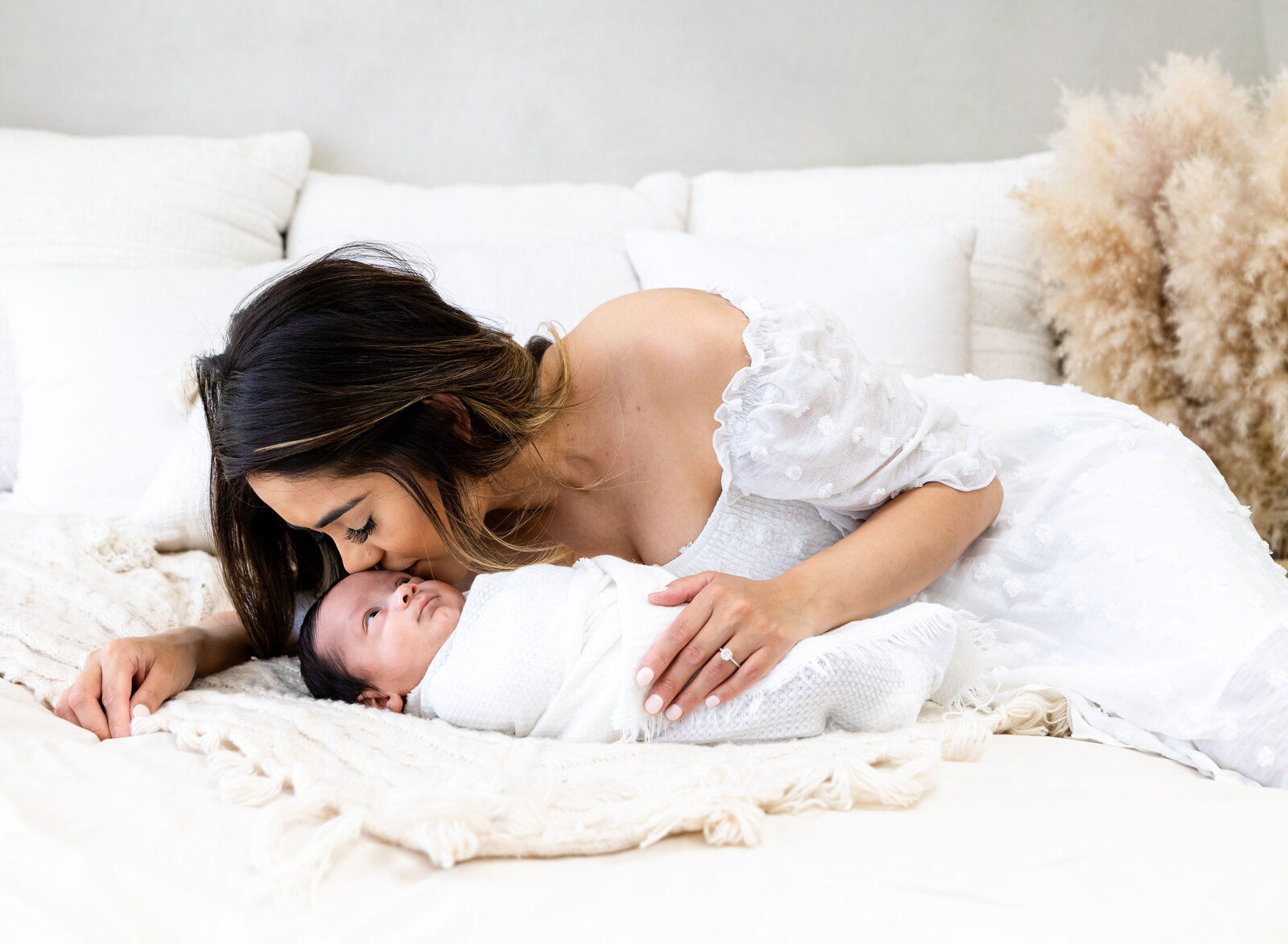 mom kissing newborn baby