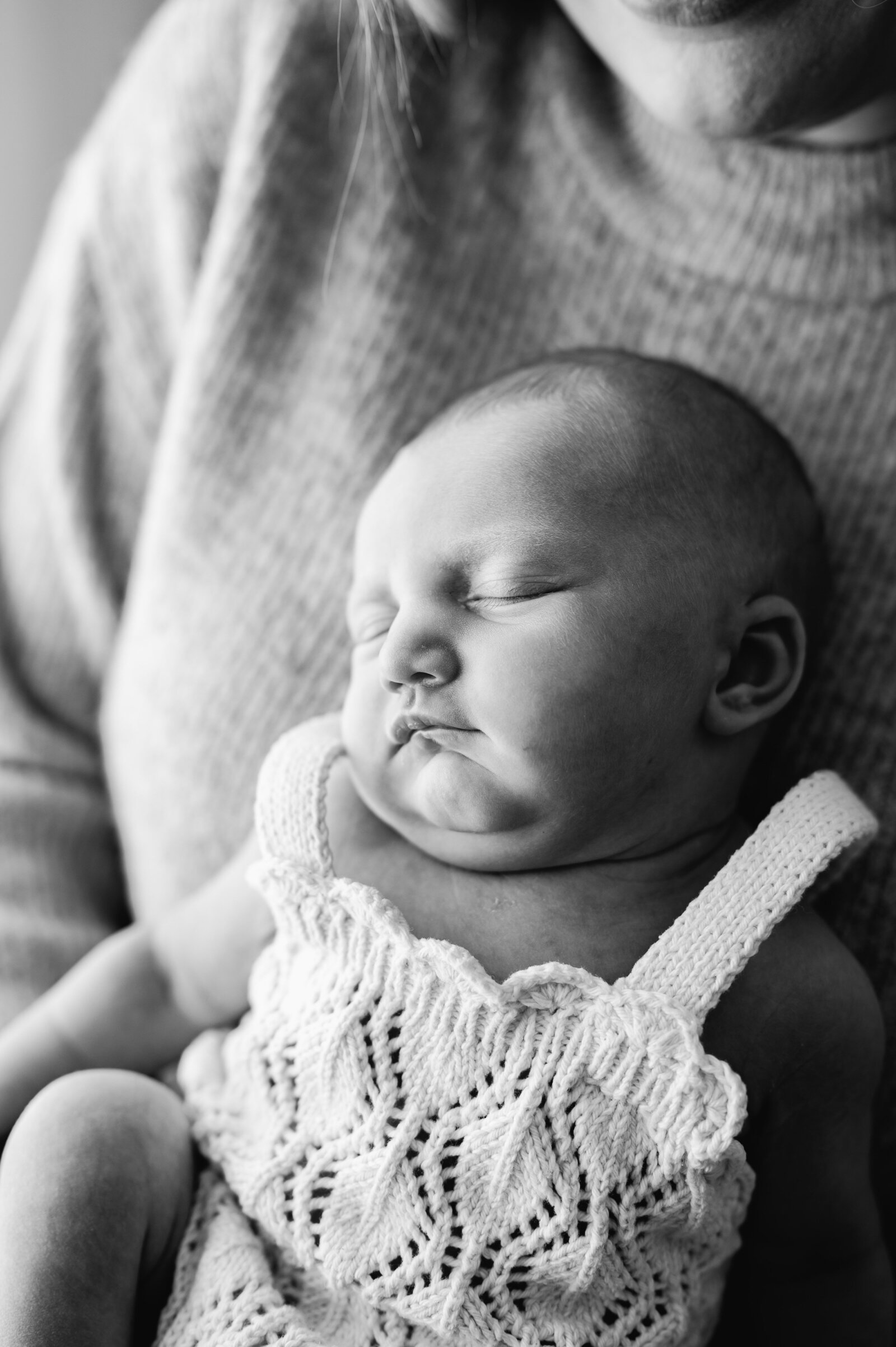 A sleeping baby leaning on his mothers chest at a newborn photoshoot in Billingshurst