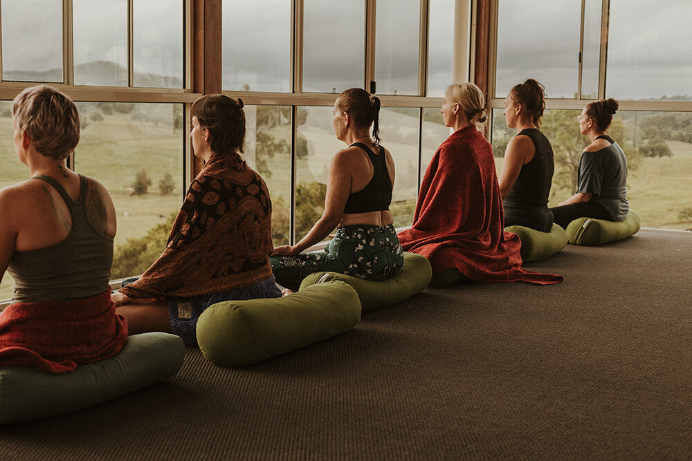 Women seated on cushions facing scenic countryside views during a meditation retreat, photographed by Sunshine Coast event photographer.
