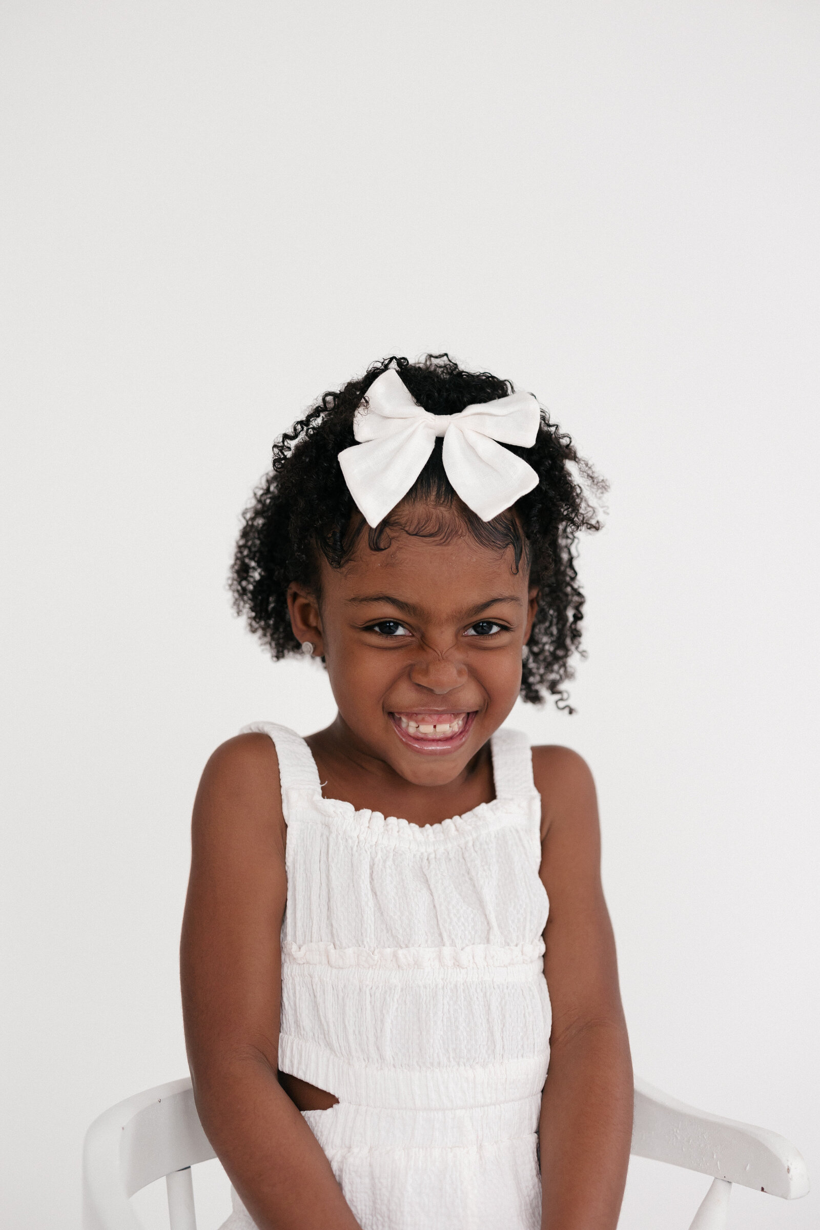 Little girl wearing a white outfit as she smiles big
