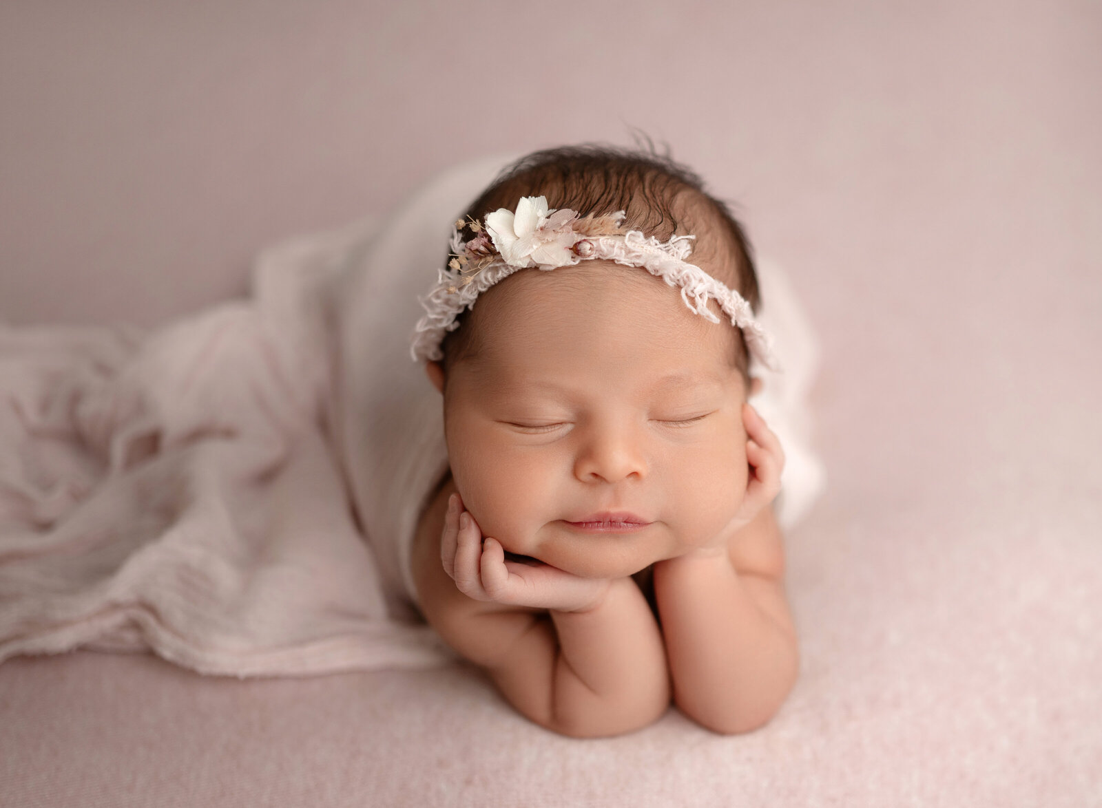 Baby sleeping with a little smirk and her hands are on her chin. Photographed by Atlanta newborn photographer.