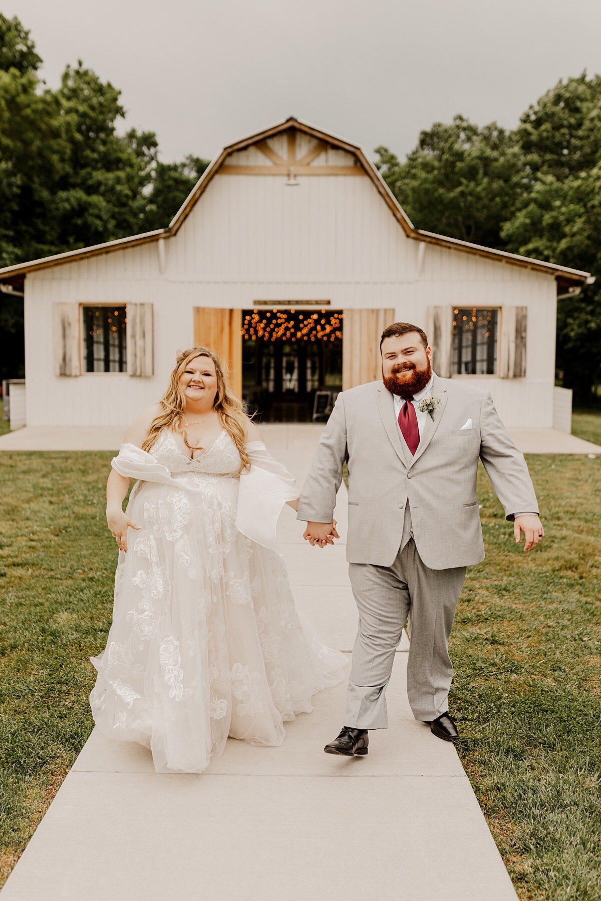 The plus size bride wearing a flowing organza gown walked down the aisle beside her plus size groom wearing a light gray suit