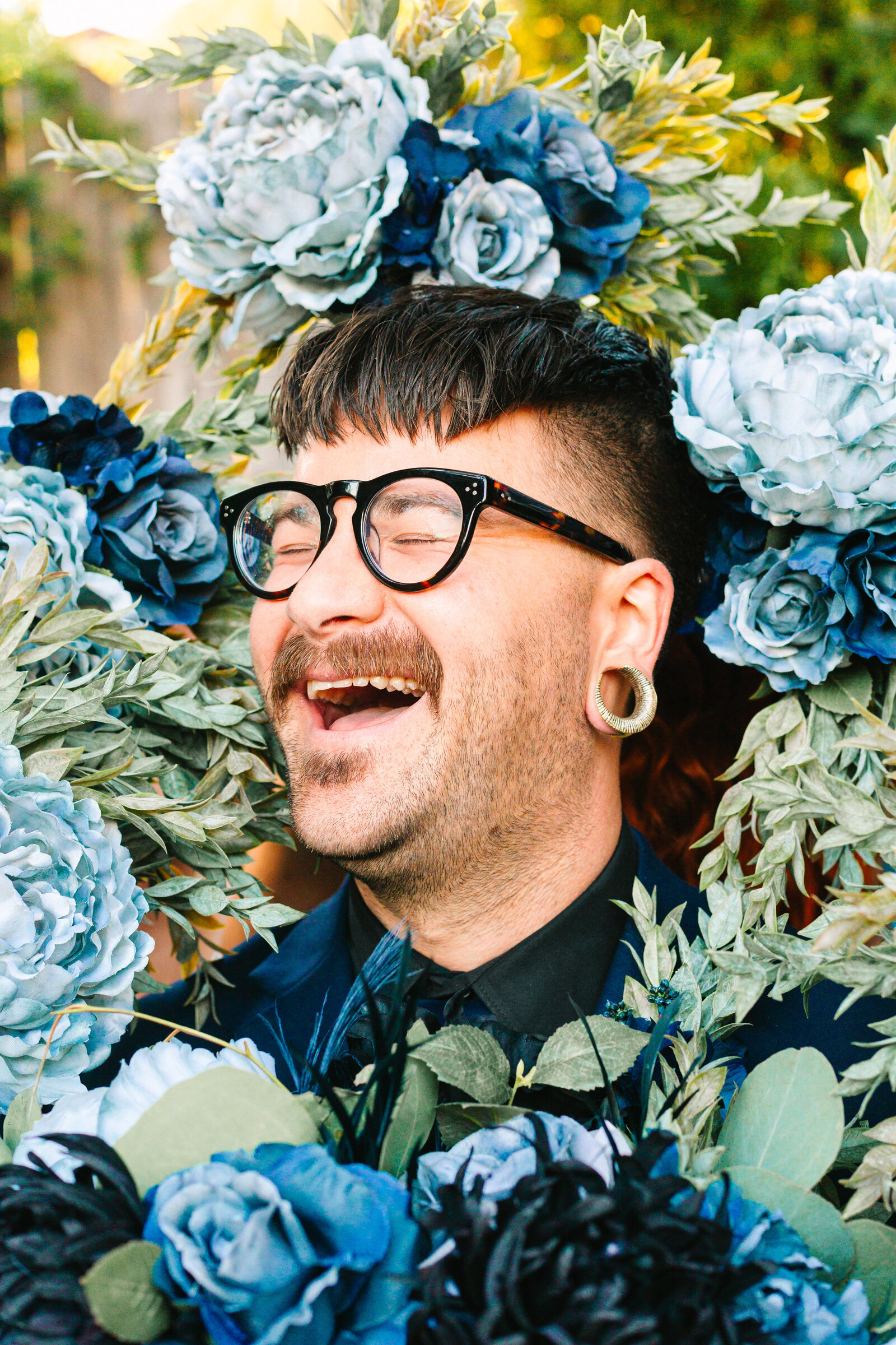 Tattooed groom with colorful wedding flowers.