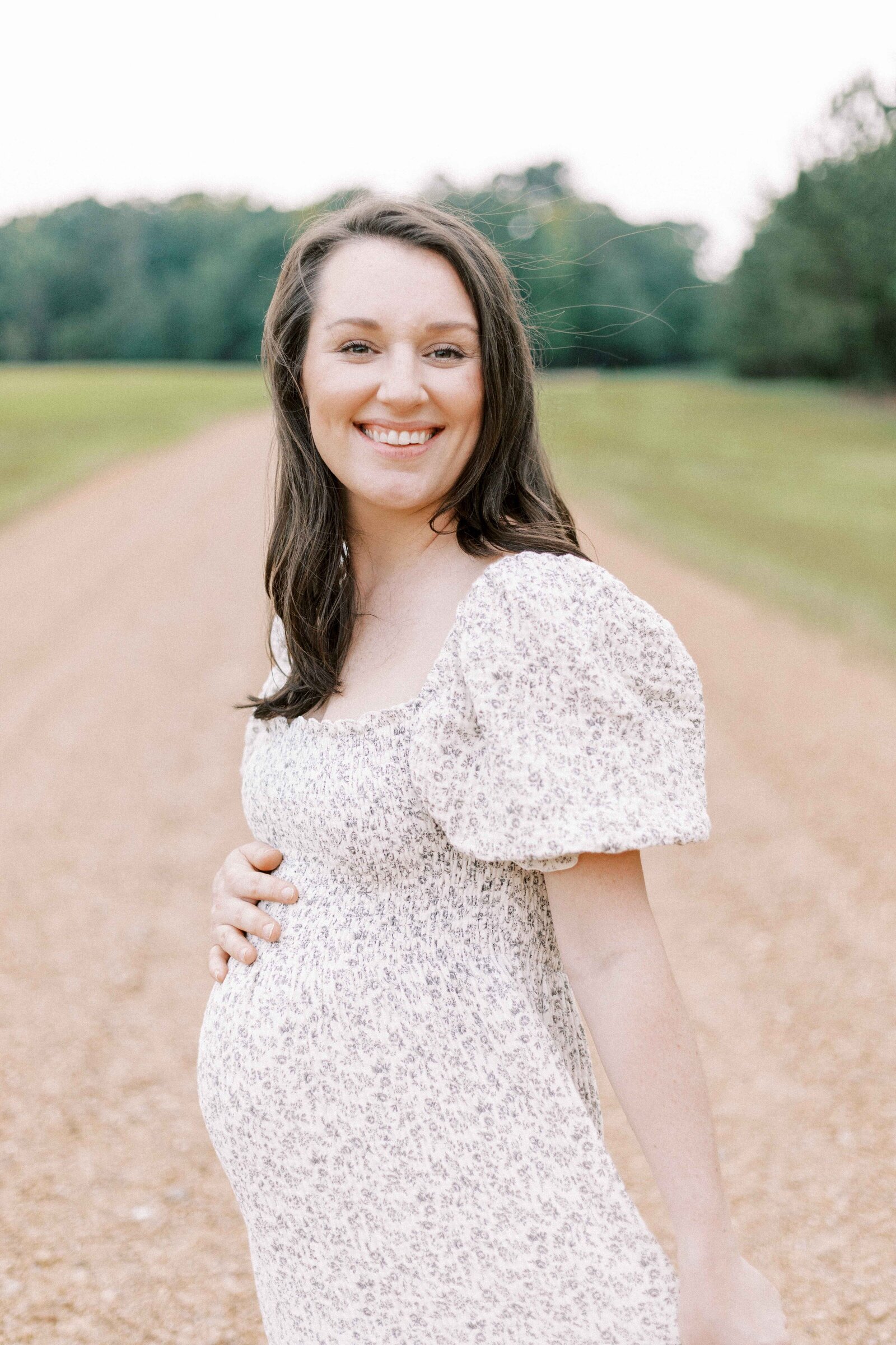 mom smiling and holding bump during peoria illinois family photos 
