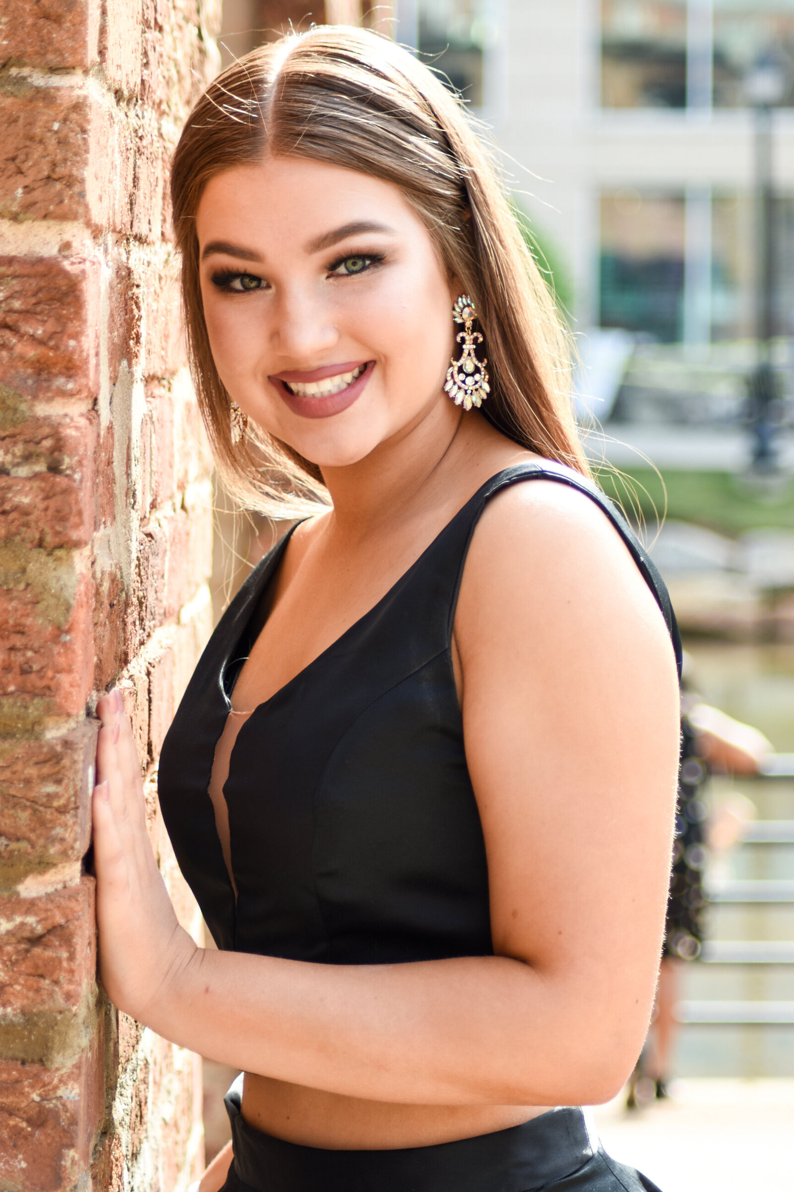 a woman leaning against a brick wall smiling at the camera photographed by Millz Photography in Greenville, SC
