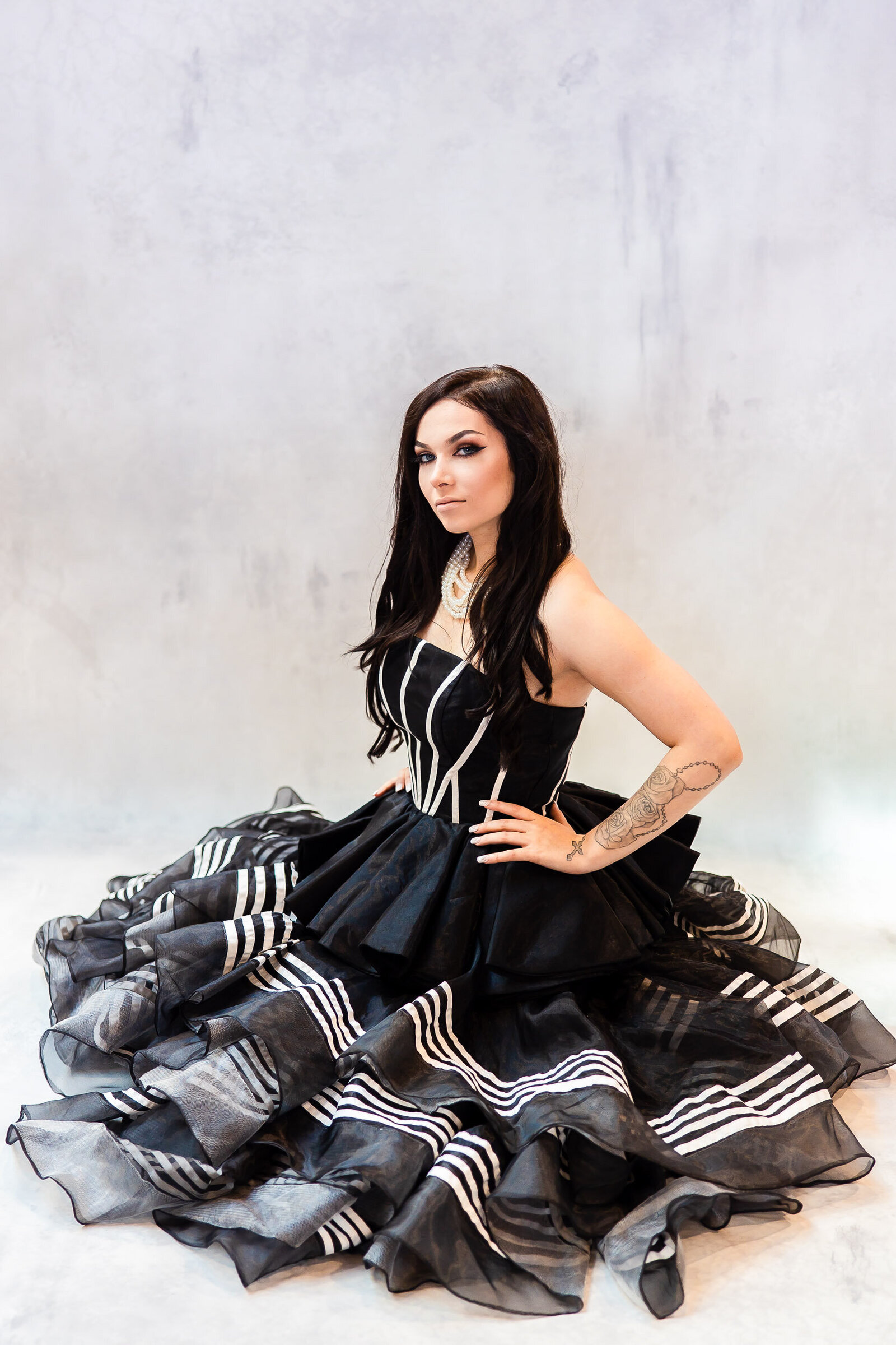 senior girl on floor in black and white dress with hand on hip