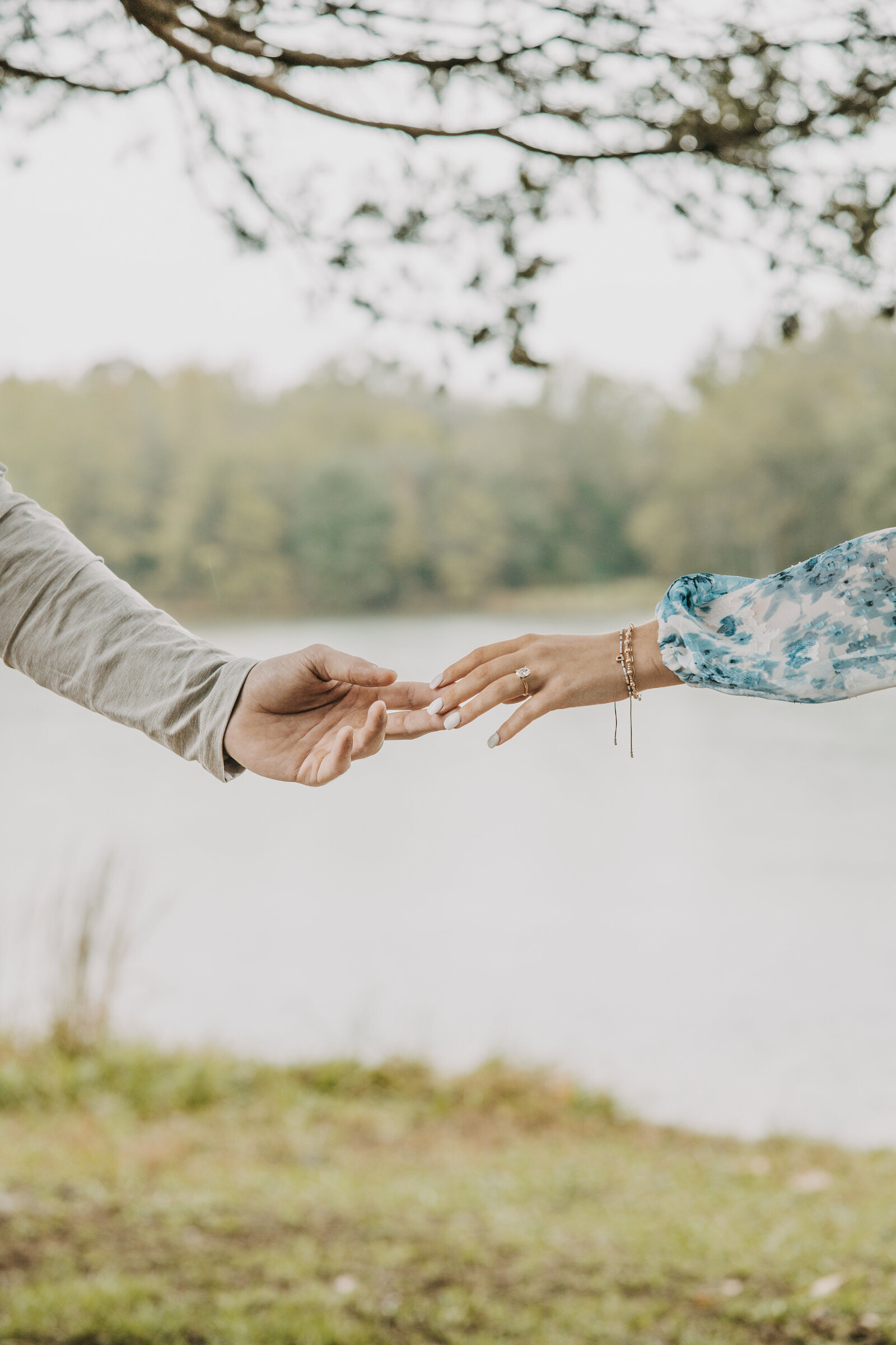 Engagement session at Shelby Farms, inspired by Michelangelo's Sistine Chapel, with two hands gently touching in front of a pond, focus on the engagement ring.