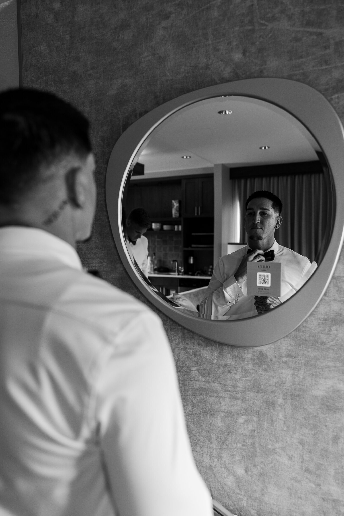 Groom straightens his tie in mirror getting ready for his Moab Wedding