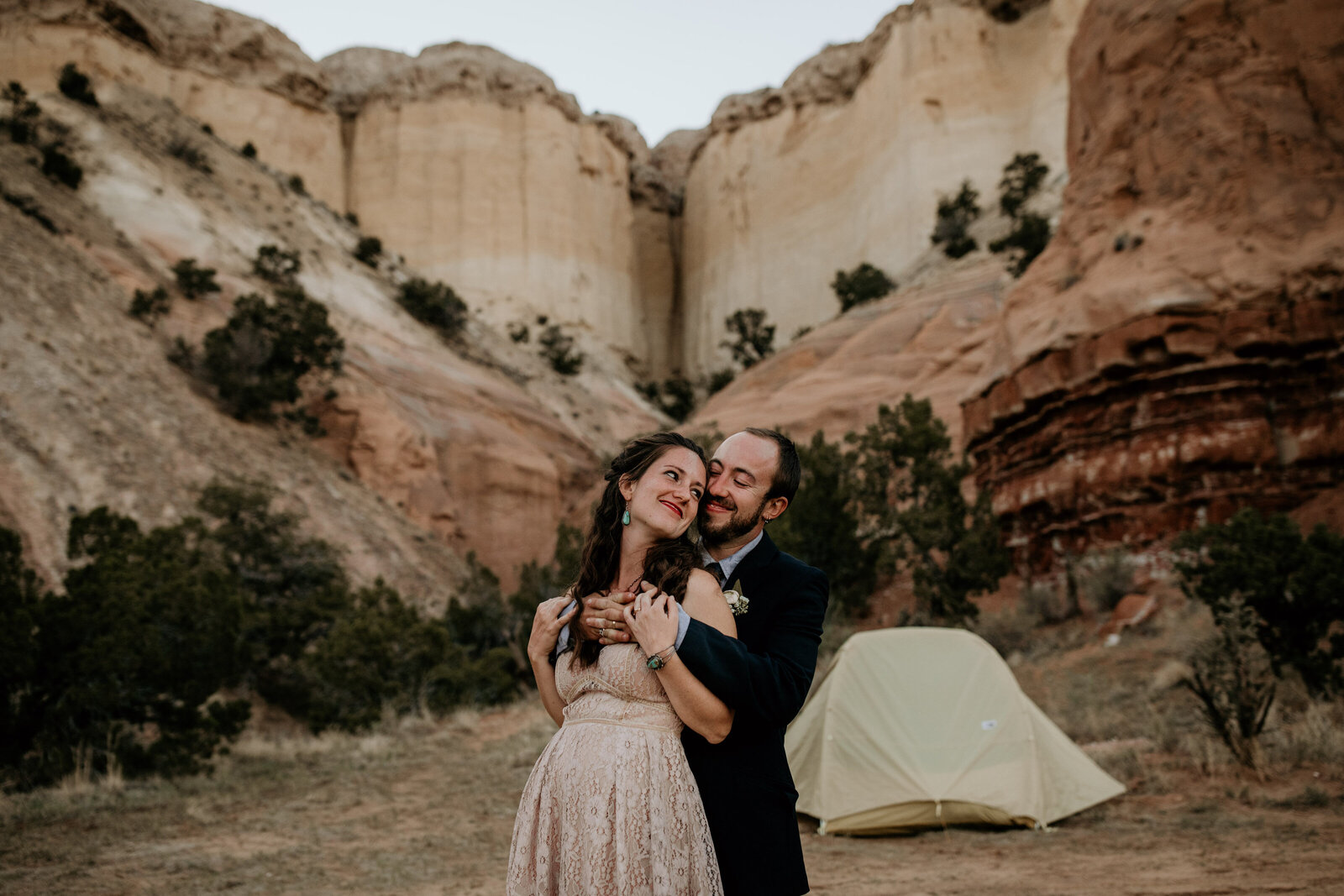 husband hugging wife from behind at their elopement campsite