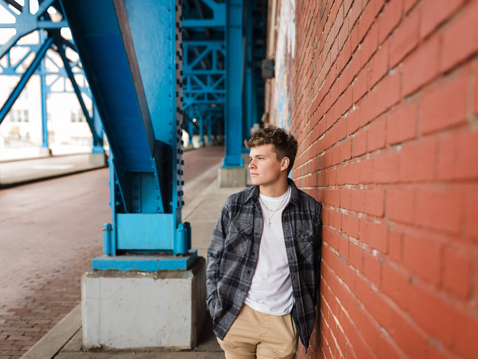 male senior leaning against brick wall for senior photos in cleveland
