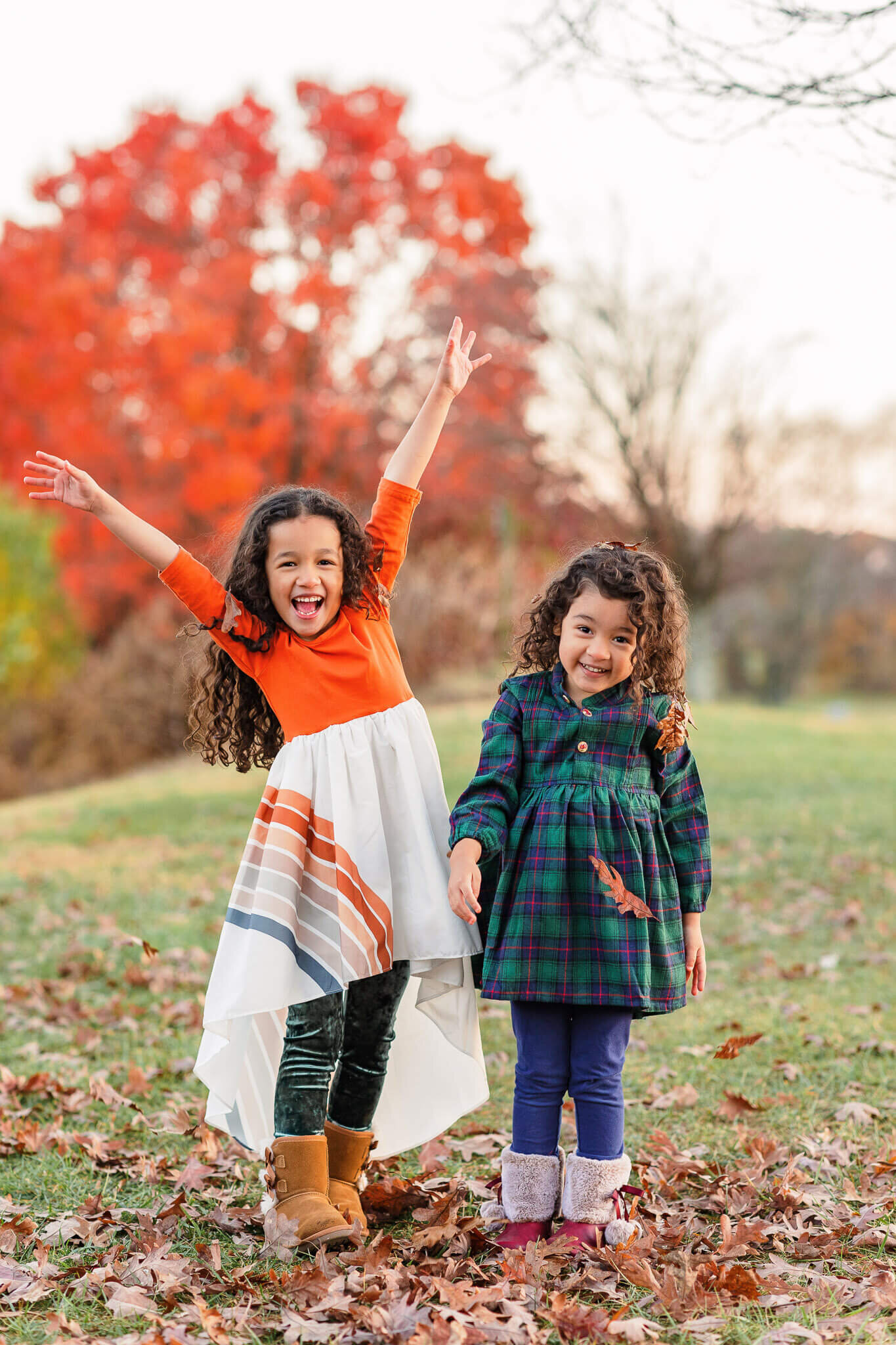 Two sisters throwing leaves in the air