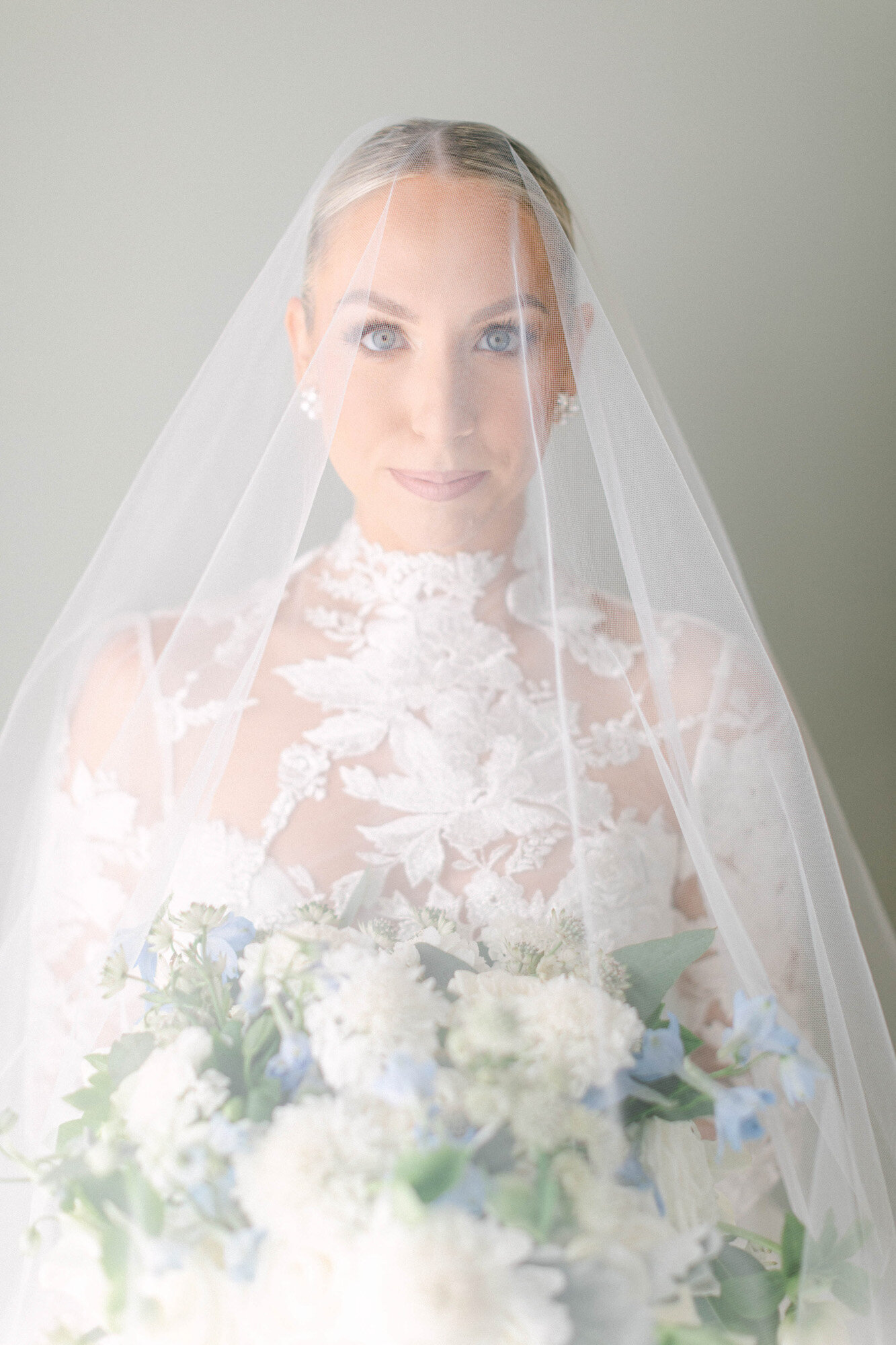bridal portrait of bride standing underneath wedding veil