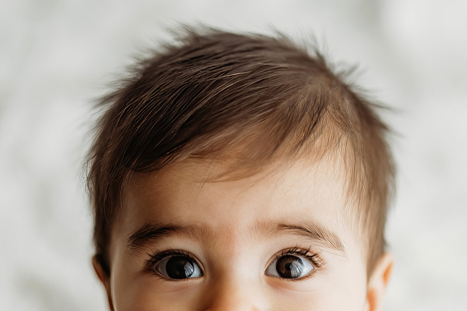 Close up of six month old baby toes and she sits on a toddler size wooden chair during her Denver milestone session