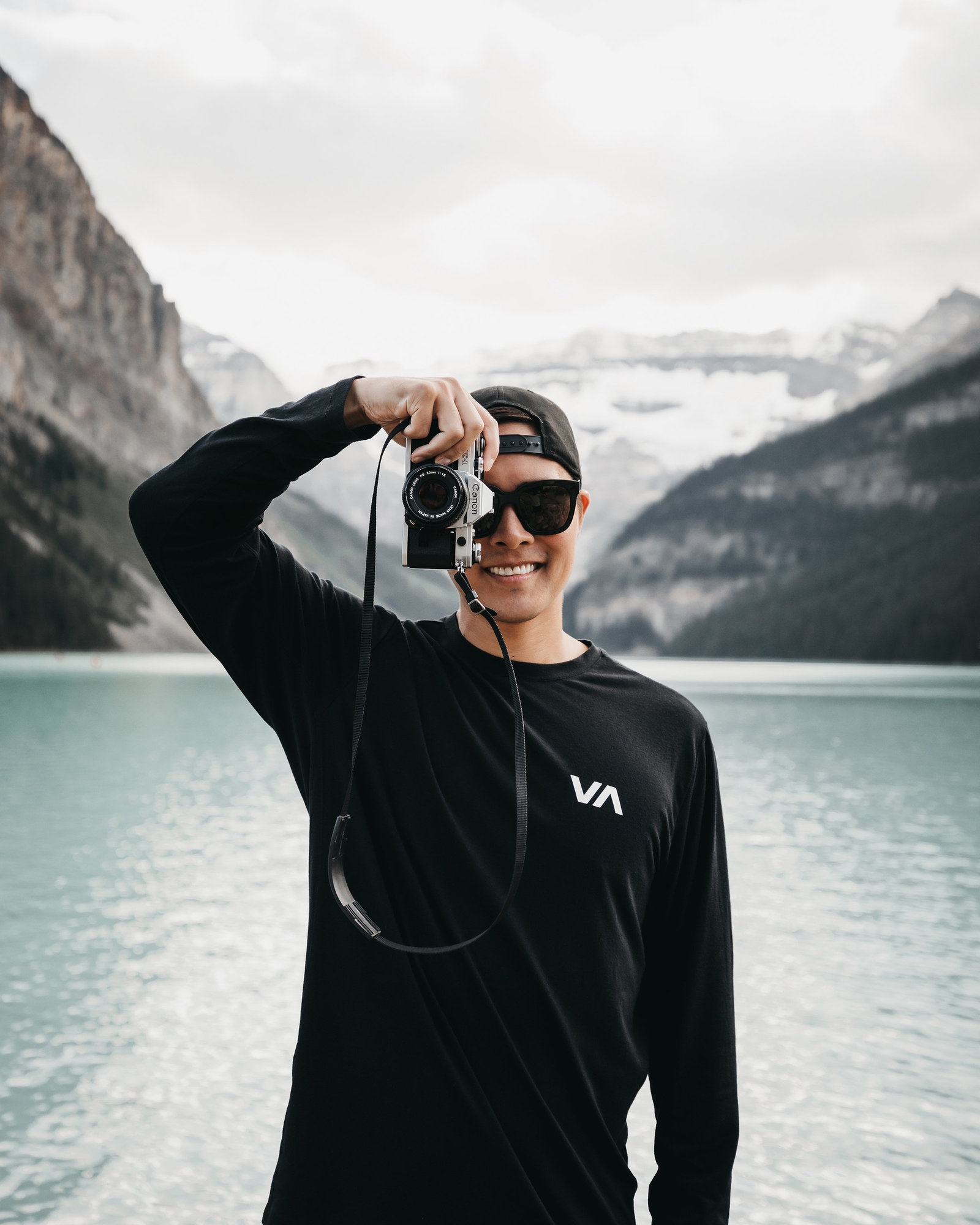 Photographer holding camera to eye in front of mountains